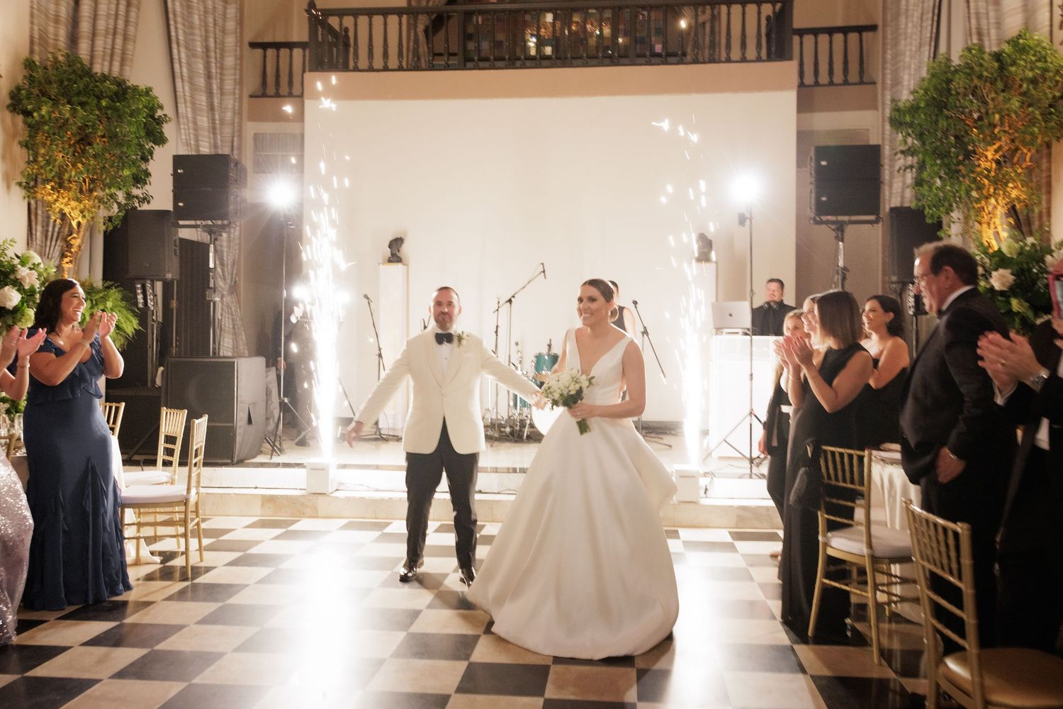 Couple celebrates their first dance with sparklers illuminating an elegant ballroom setting.