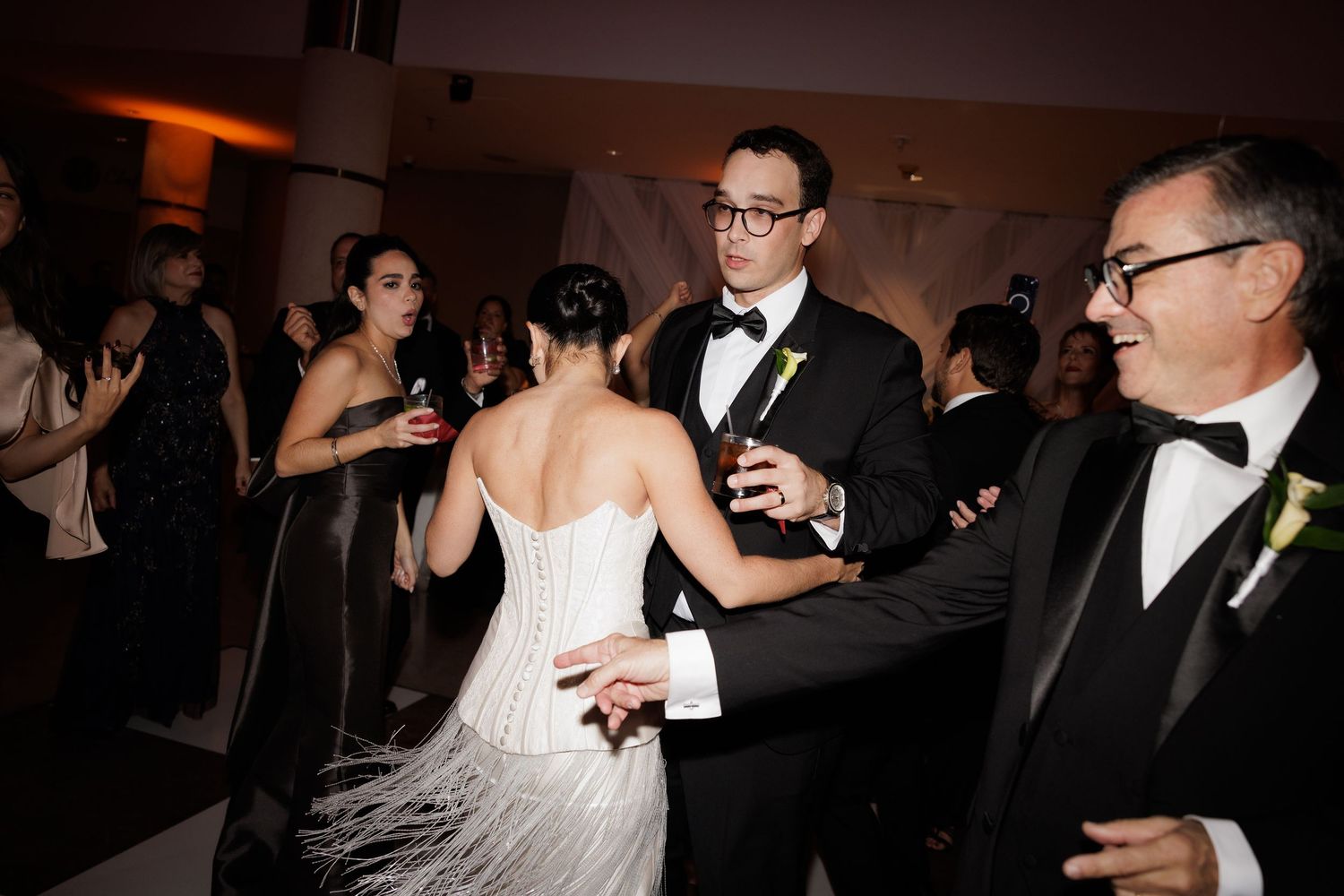 Wedding celebration on the dance floor with guests in formal attire enjoying the festivities.