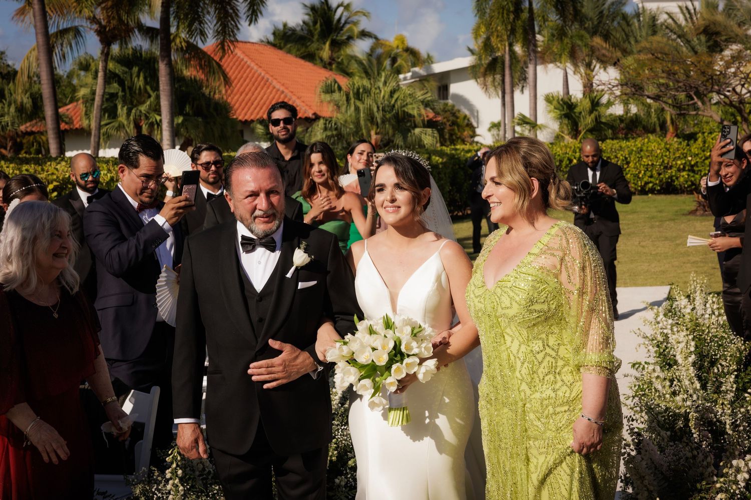 Wedding party celebrating with family and guests outdoors among palm trees at a sunny Florida reception venue.
