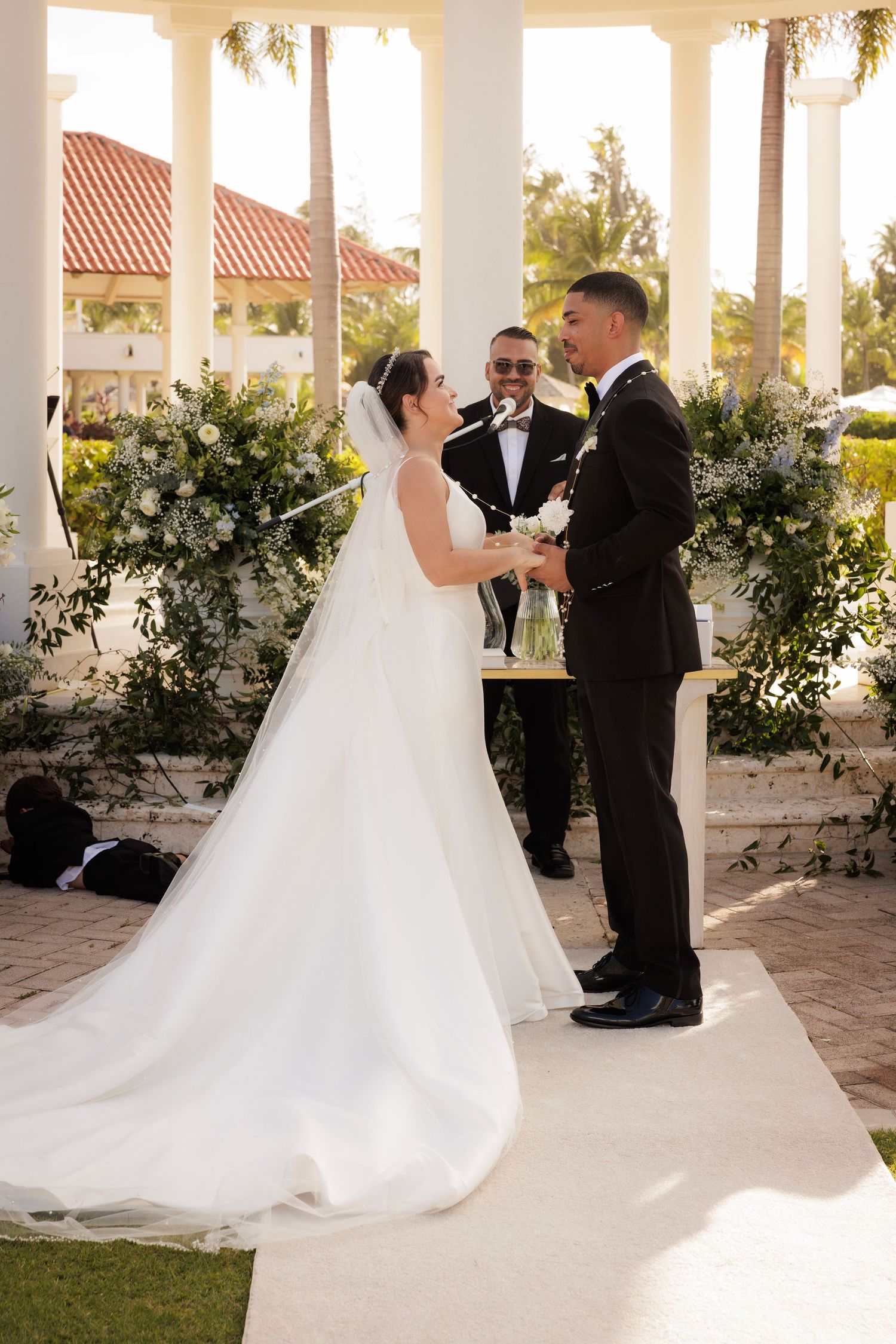 A couple sharing their first dance under an elegant covered pavilion at sunset surrounded by potted greenery.
