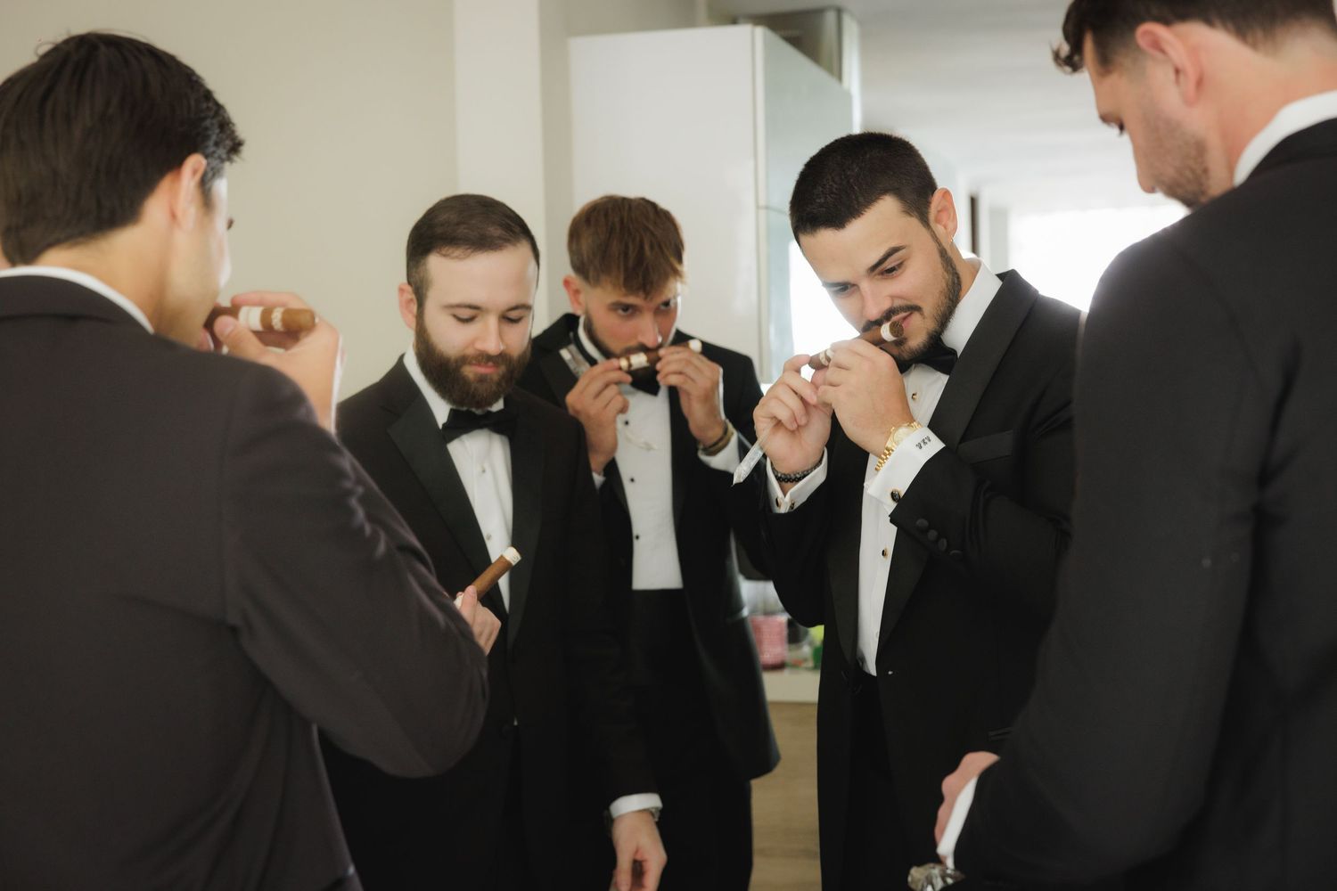 Group of groomsmen in black tuxedos sharing a lighthearted moment.