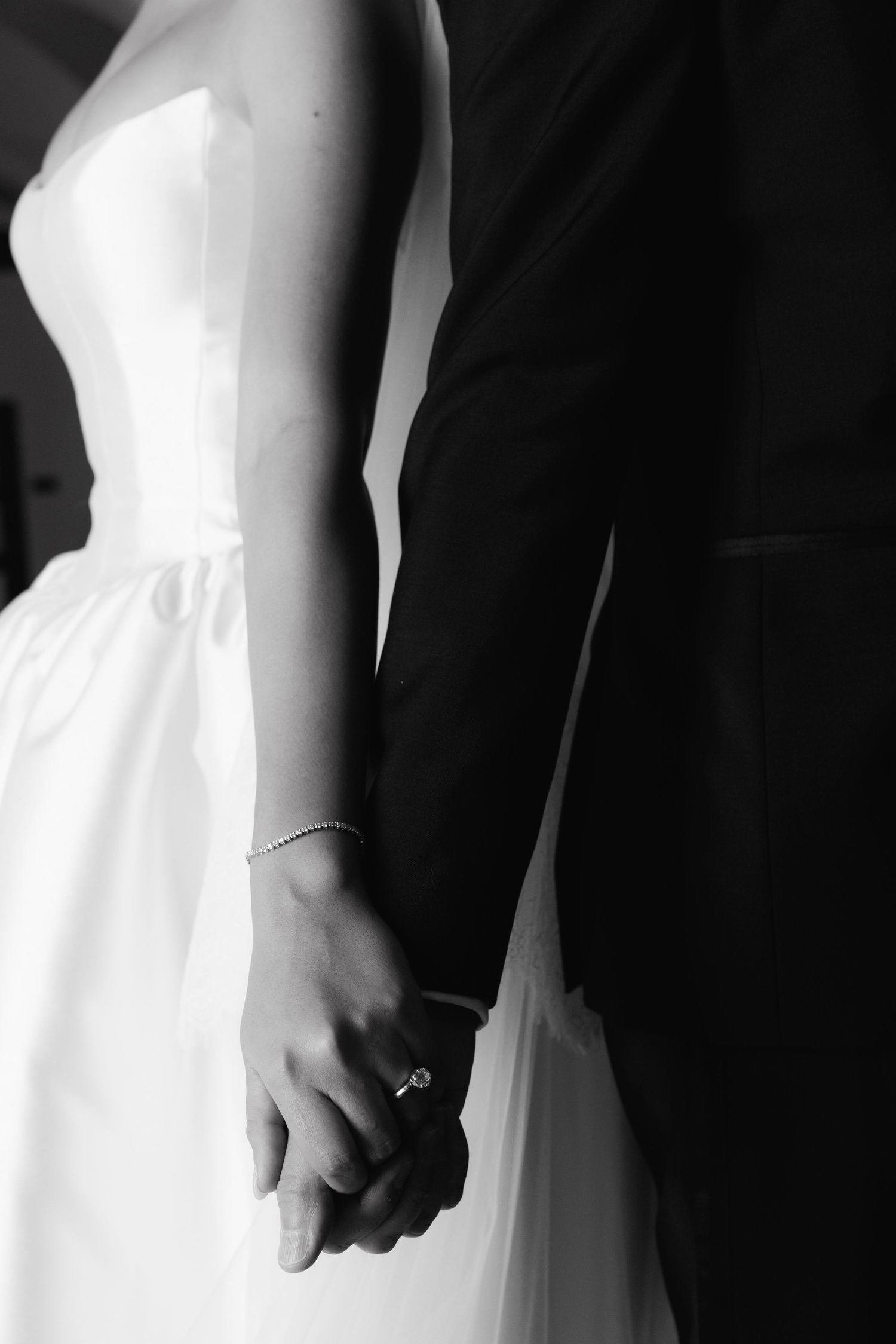 Black and white image of a couple holding hands during their wedding ceremony.