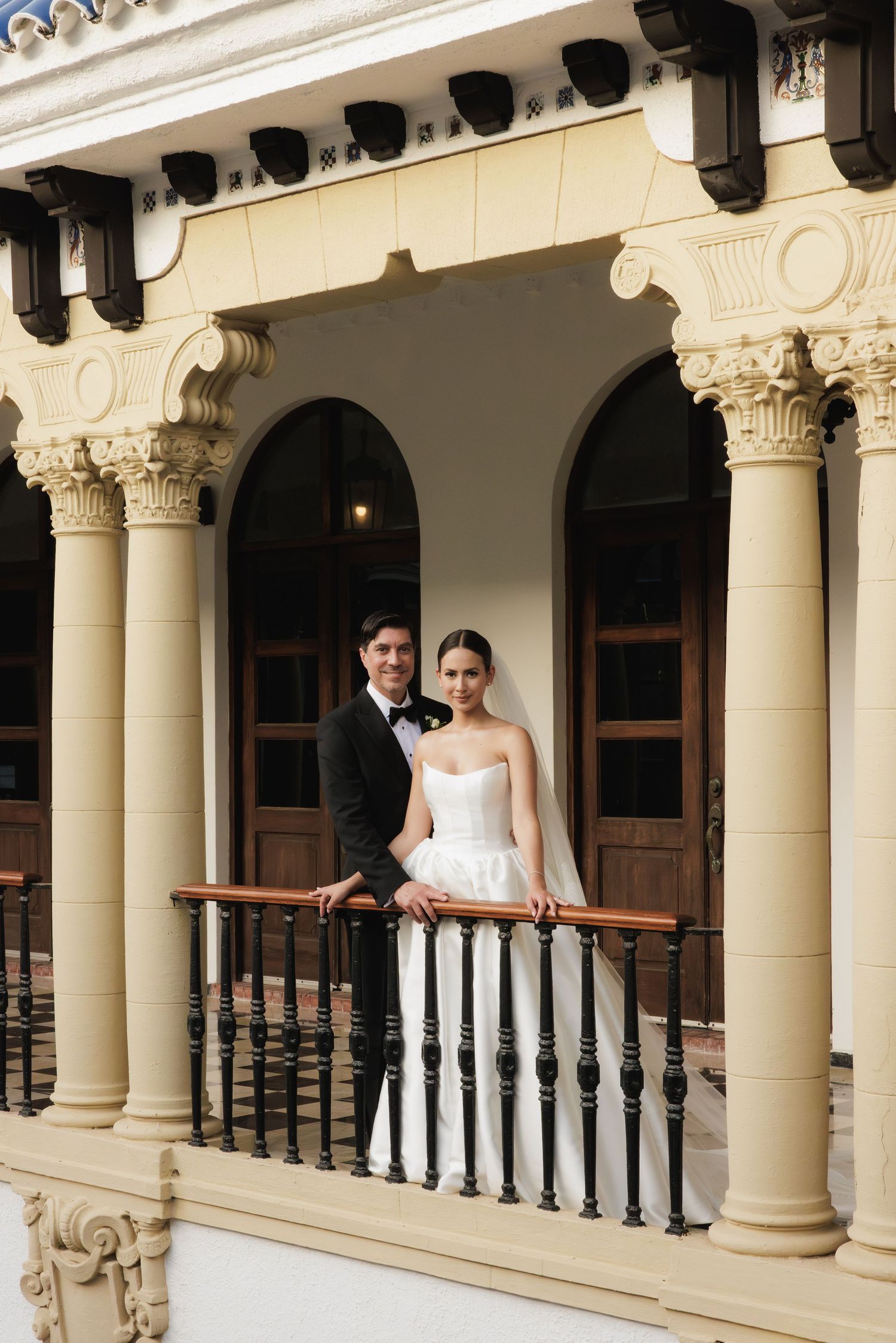 Elegant wedding portraits taken in a classical colonnade with ornate architectural details.