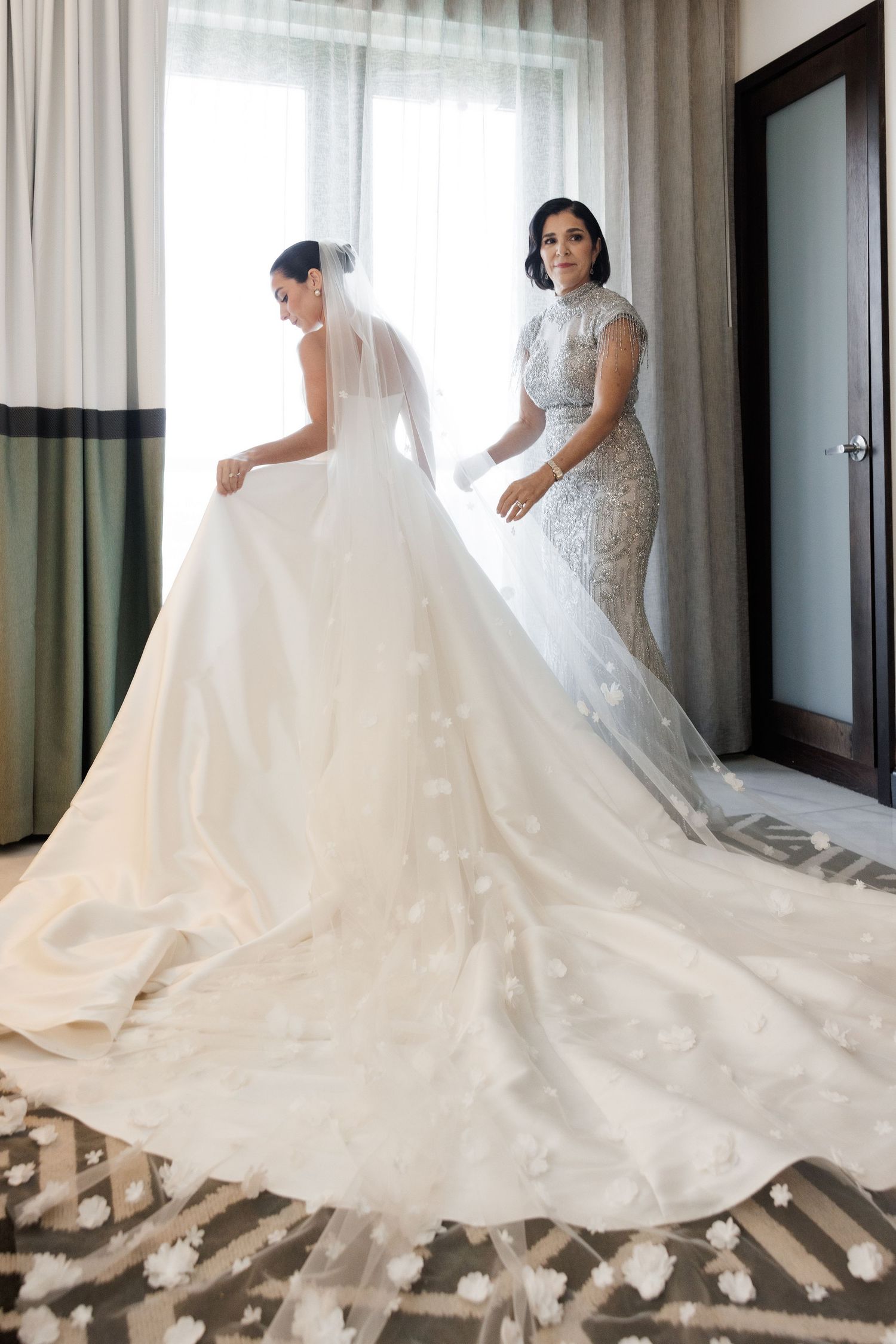 A wedding dress with a dramatic cathedral train is arranged on the floor showing its elegant flow and details.