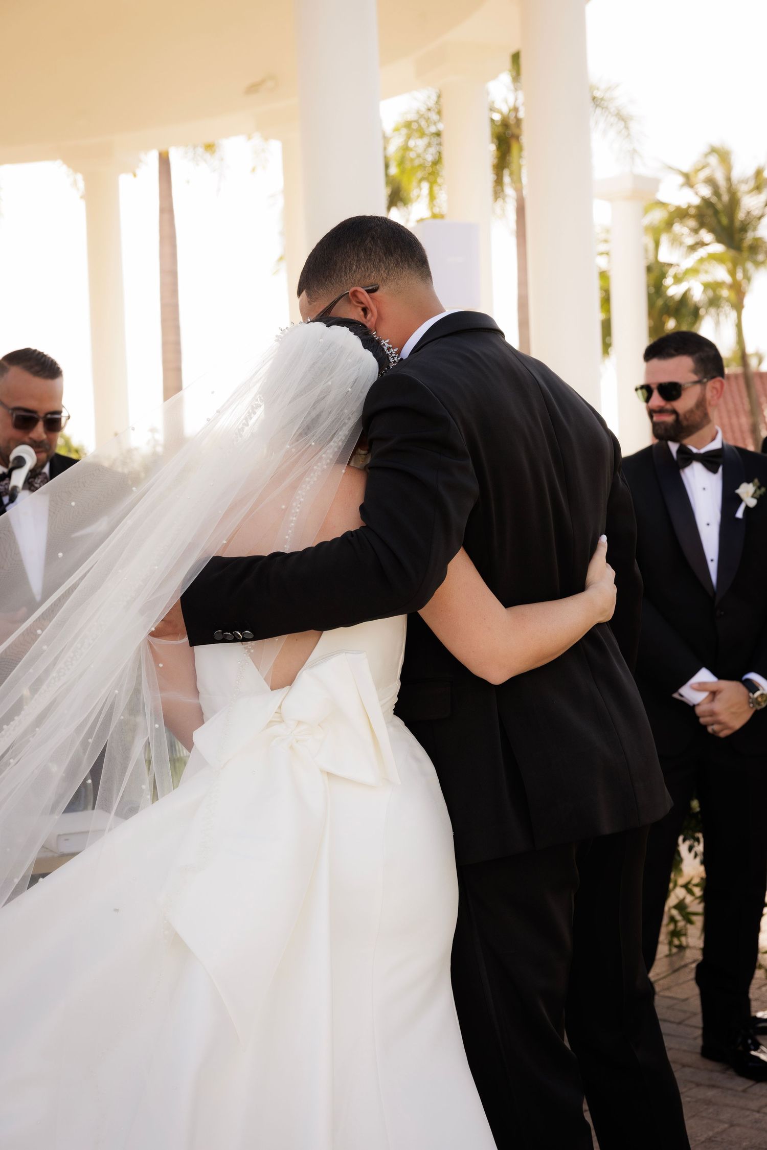 A series of romantic wedding photographs showing embraces between couples in formal attire with flowing white veils.