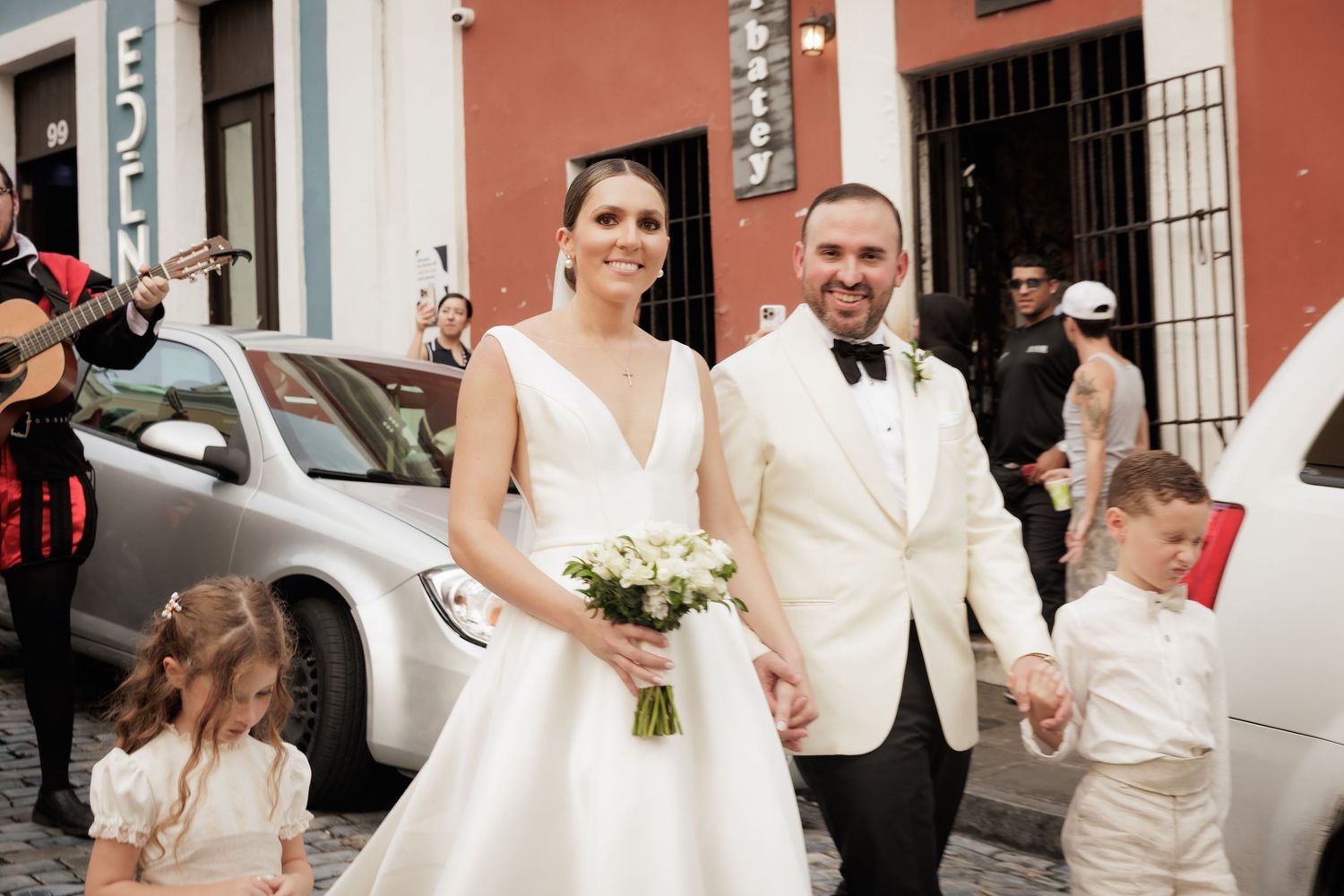 Wedding party gathered outside historic buildings with pastel-colored facades.