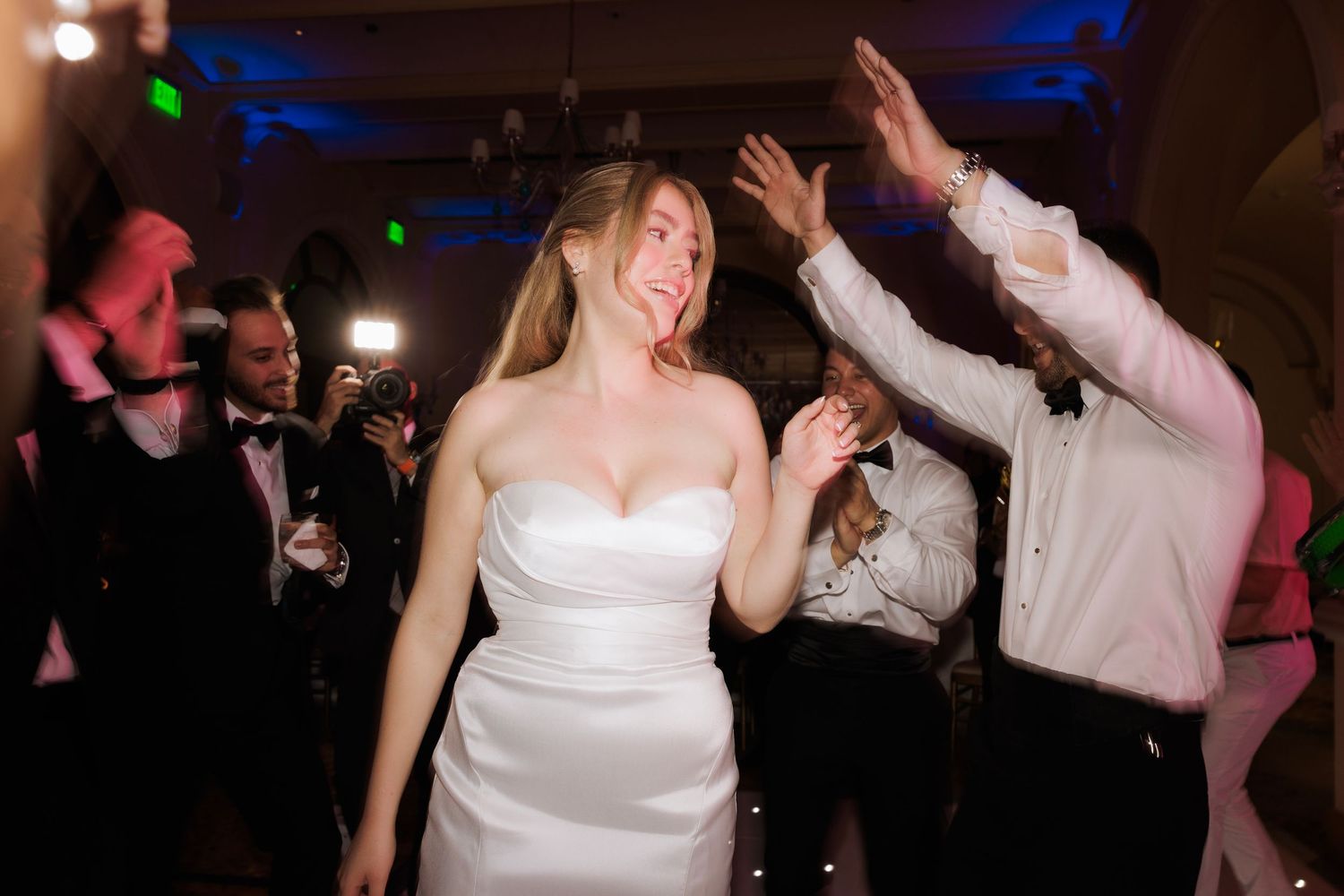 Dance floor at wedding reception with blue lighting and guests celebrating.