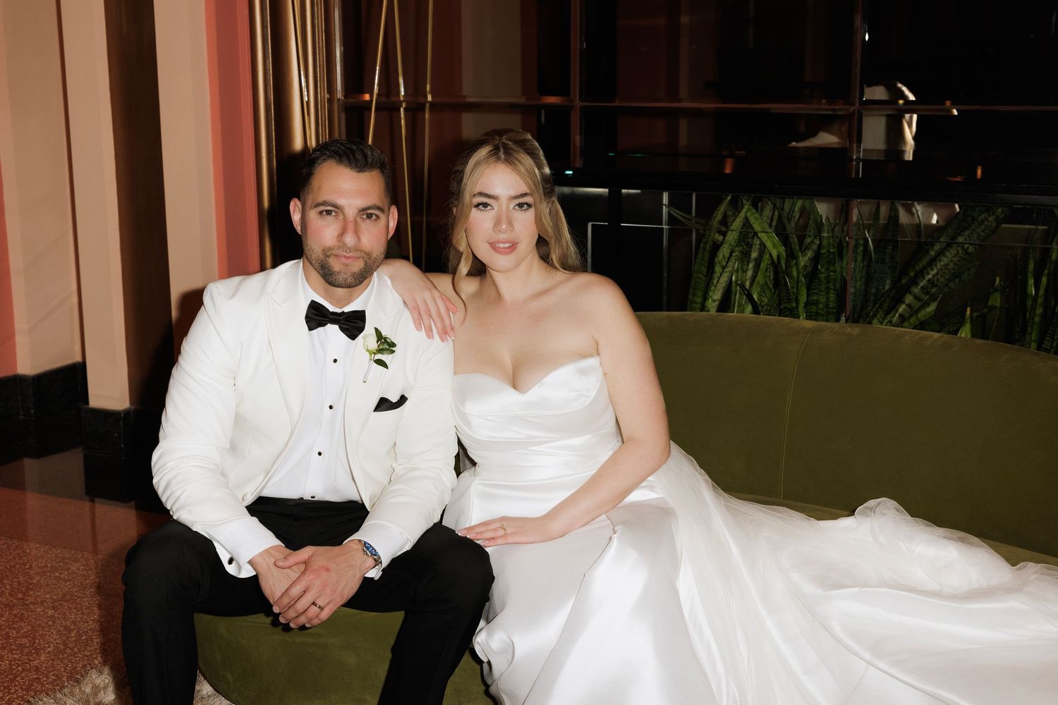 Wedding couple poses together on a carpeted floor in elegant black and white formal attire.