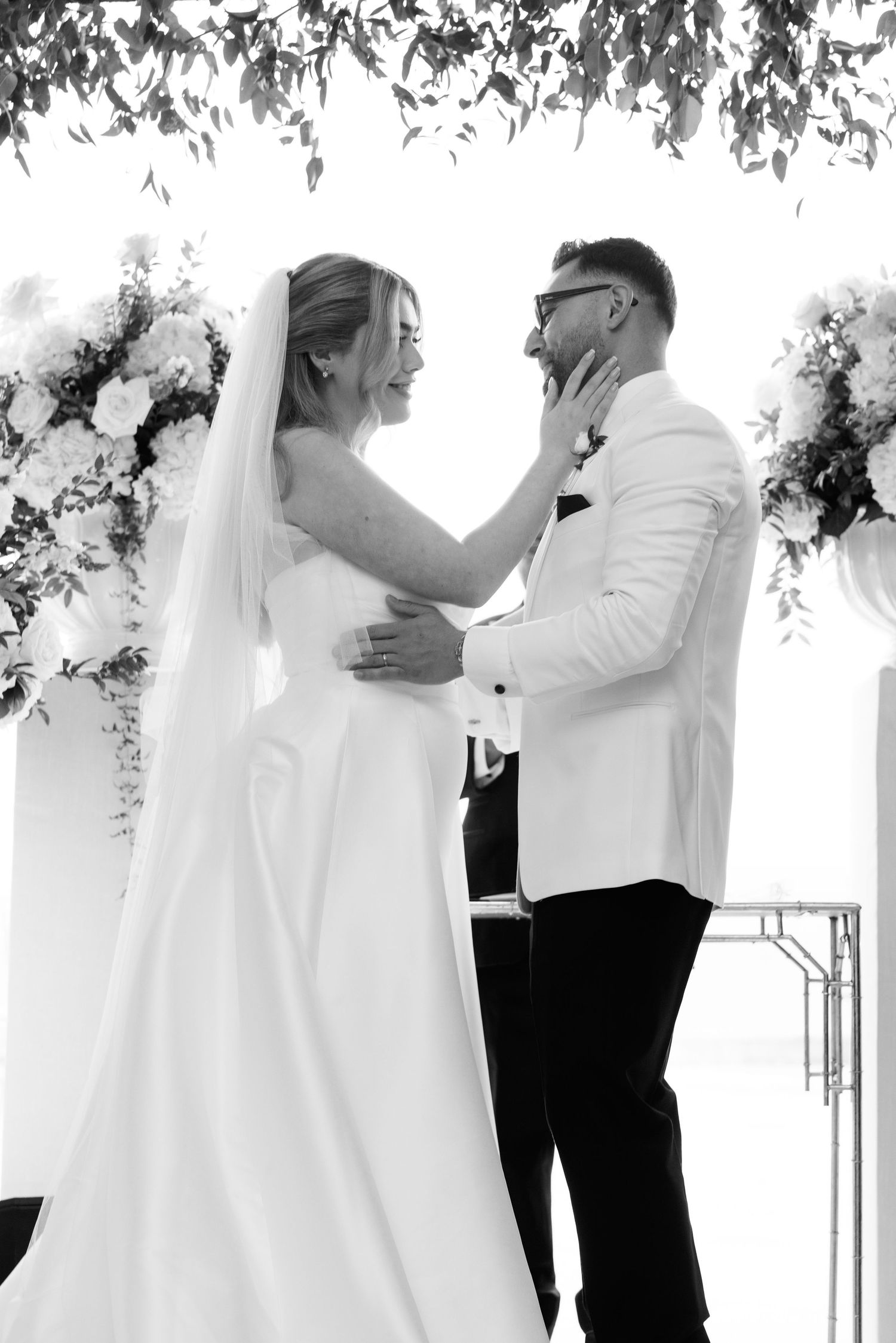 Black and white photos capture intimate first look moments under hanging foliage.