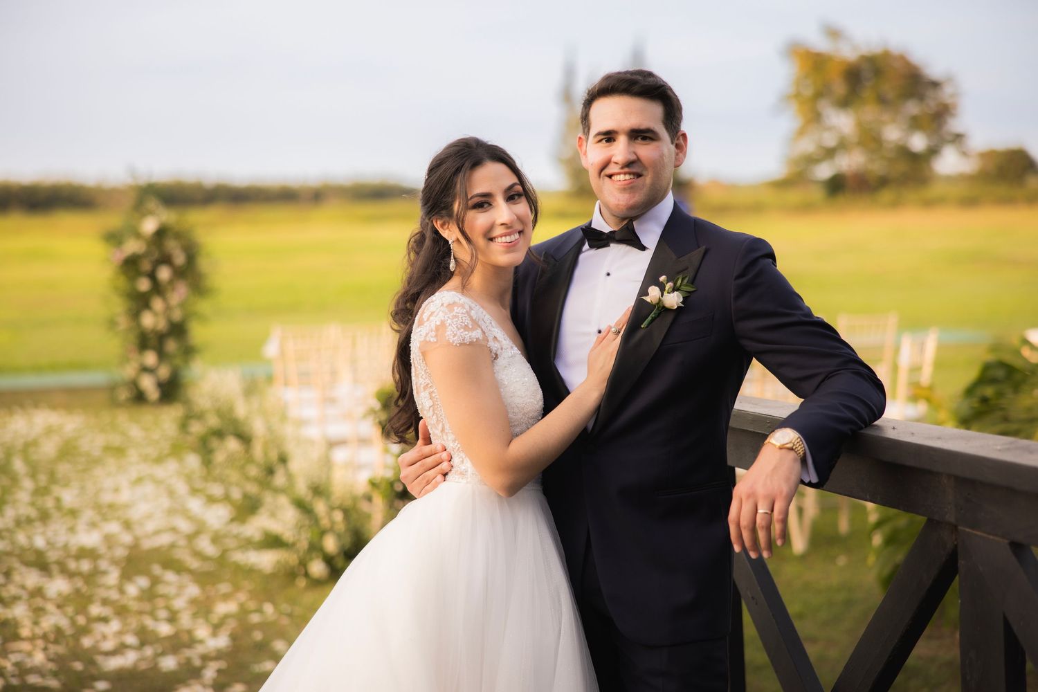 Elegant wedding couple shares romantic moments on a rustic wooden deck surrounded by greenery.