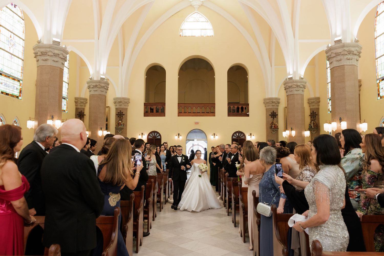 Wedding ceremony in a grand cathedral with arched ceilings and ornate architectural details.