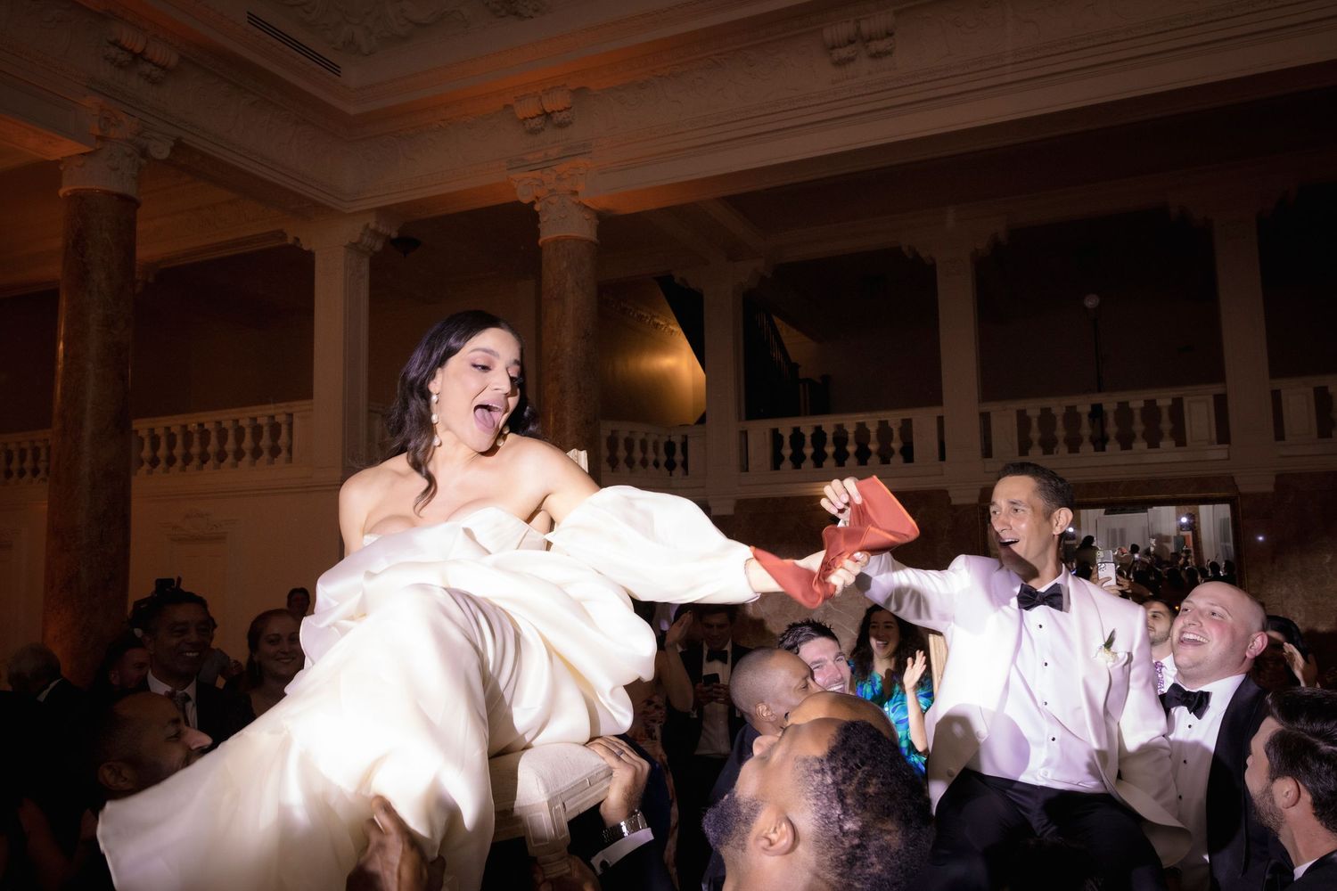 Celebratory moment as wedding guests lift and carry someone during a lively dance party.