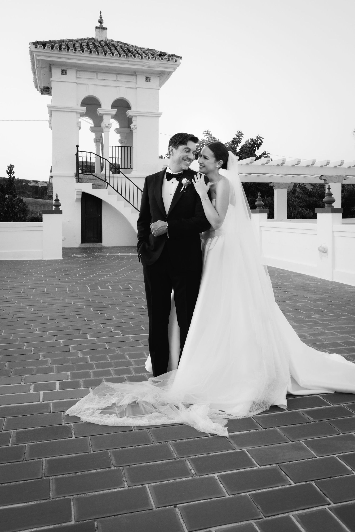 A black and white wedding photo series showing a couple on a tiled rooftop terrace with architectural details.