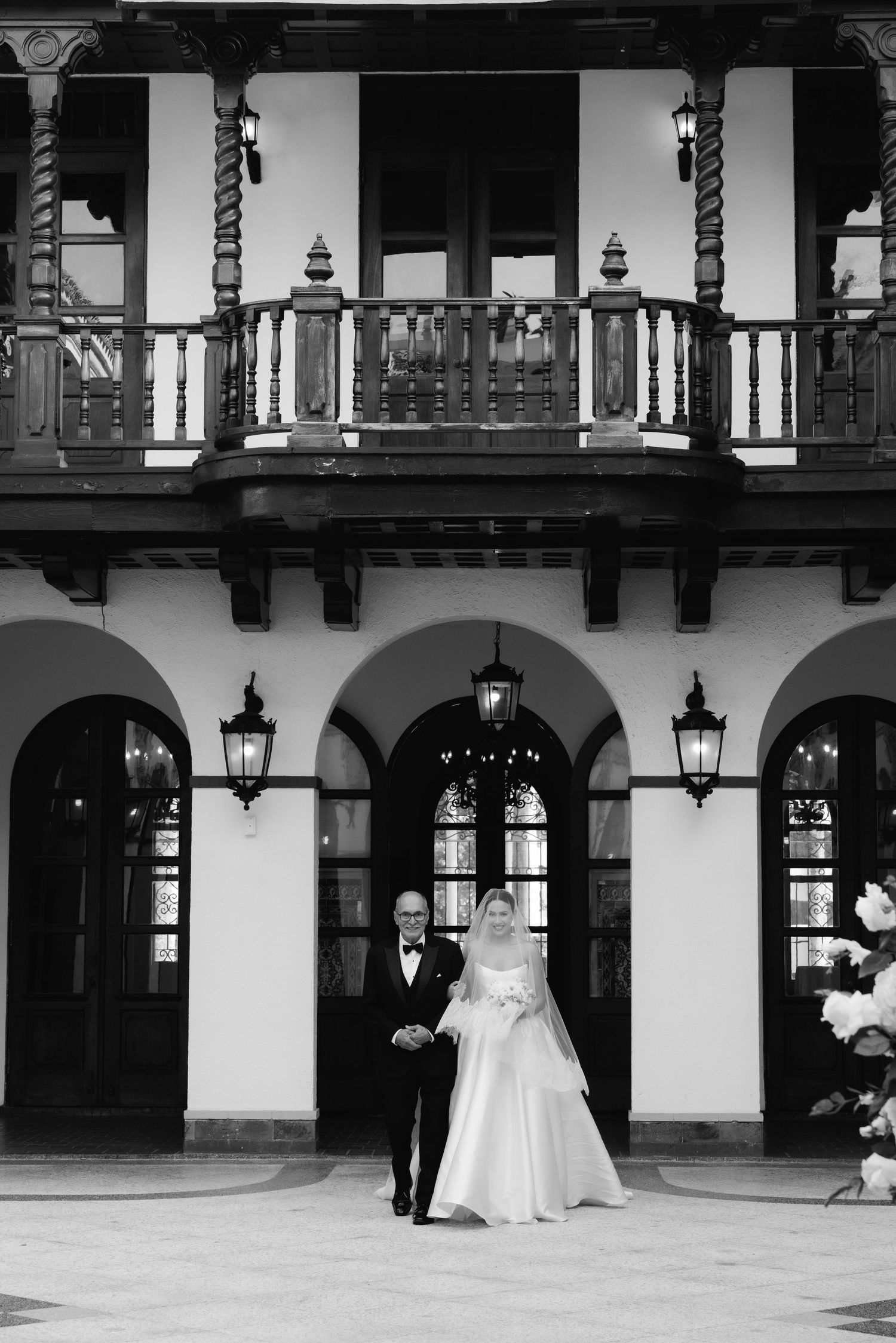 A wedding dress displayed in an elegant Spanish colonial style courtyard with arches and lanterns.