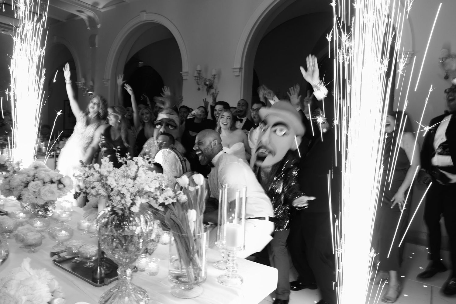 Wedding couple pouring champagne into a tower of glasses with sparklers creating a magical ambiance.