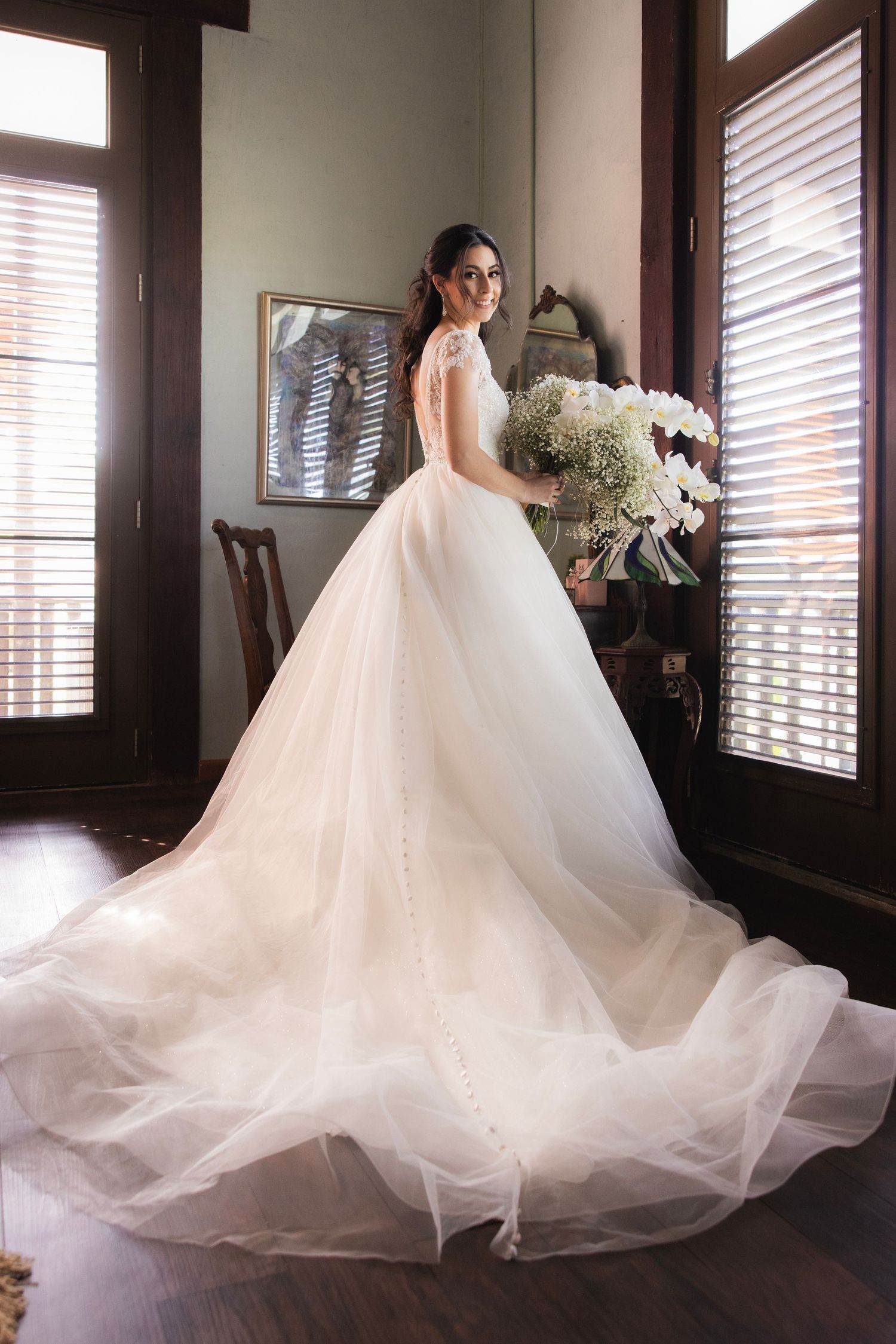 Dramatic series of bridal gown images showing flowing white tulle dress trailing across dark hardwood floors.