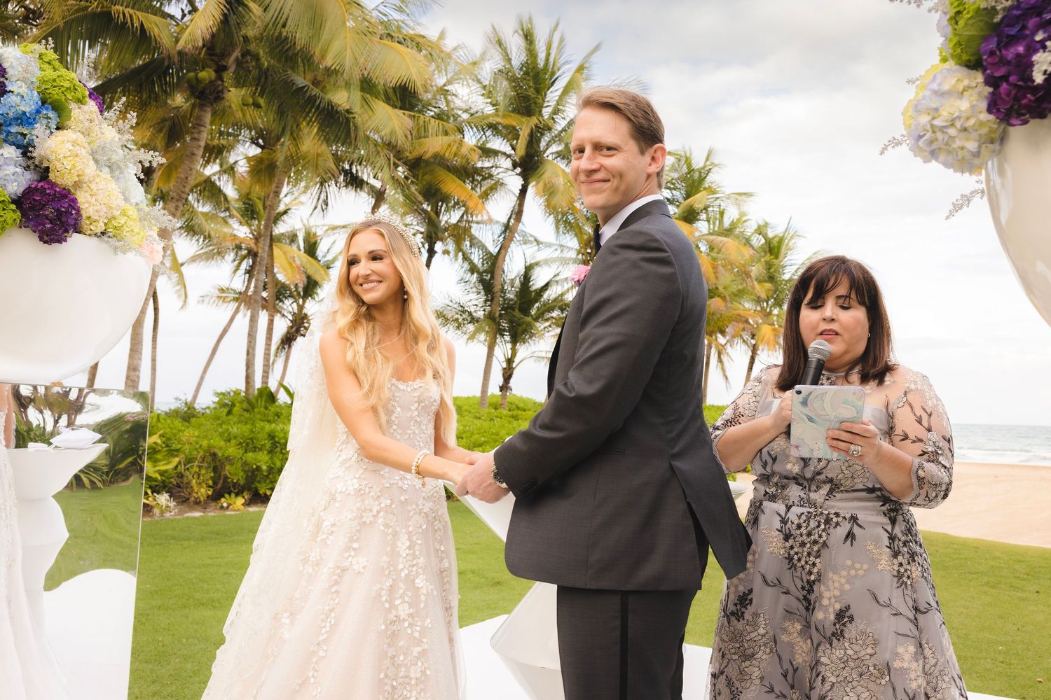 Beach wedding ceremony with oceanfront views, palm trees, and floral decorations in Hawaii.