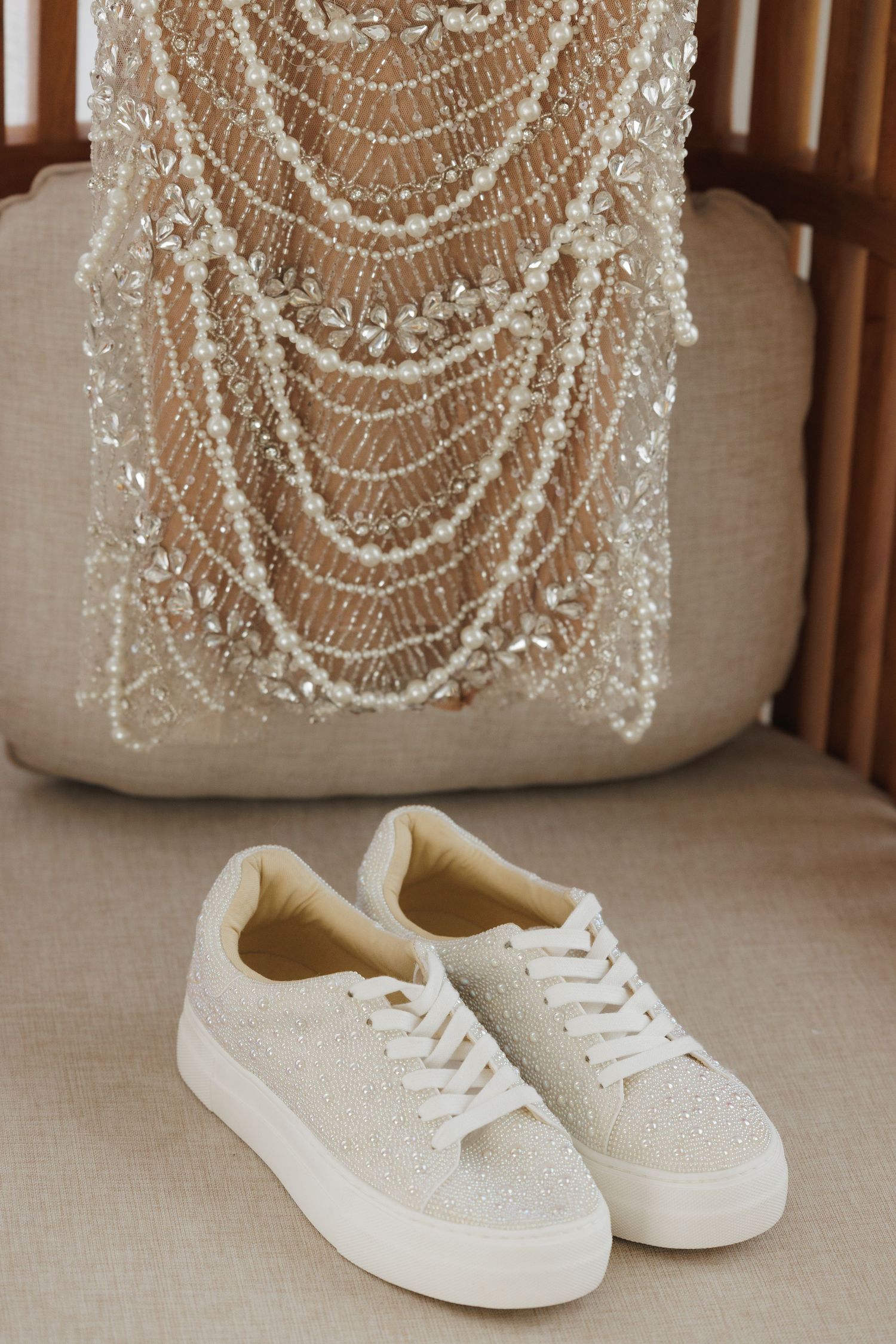 White glittery sneakers placed beneath intricate beaded wedding dress details.