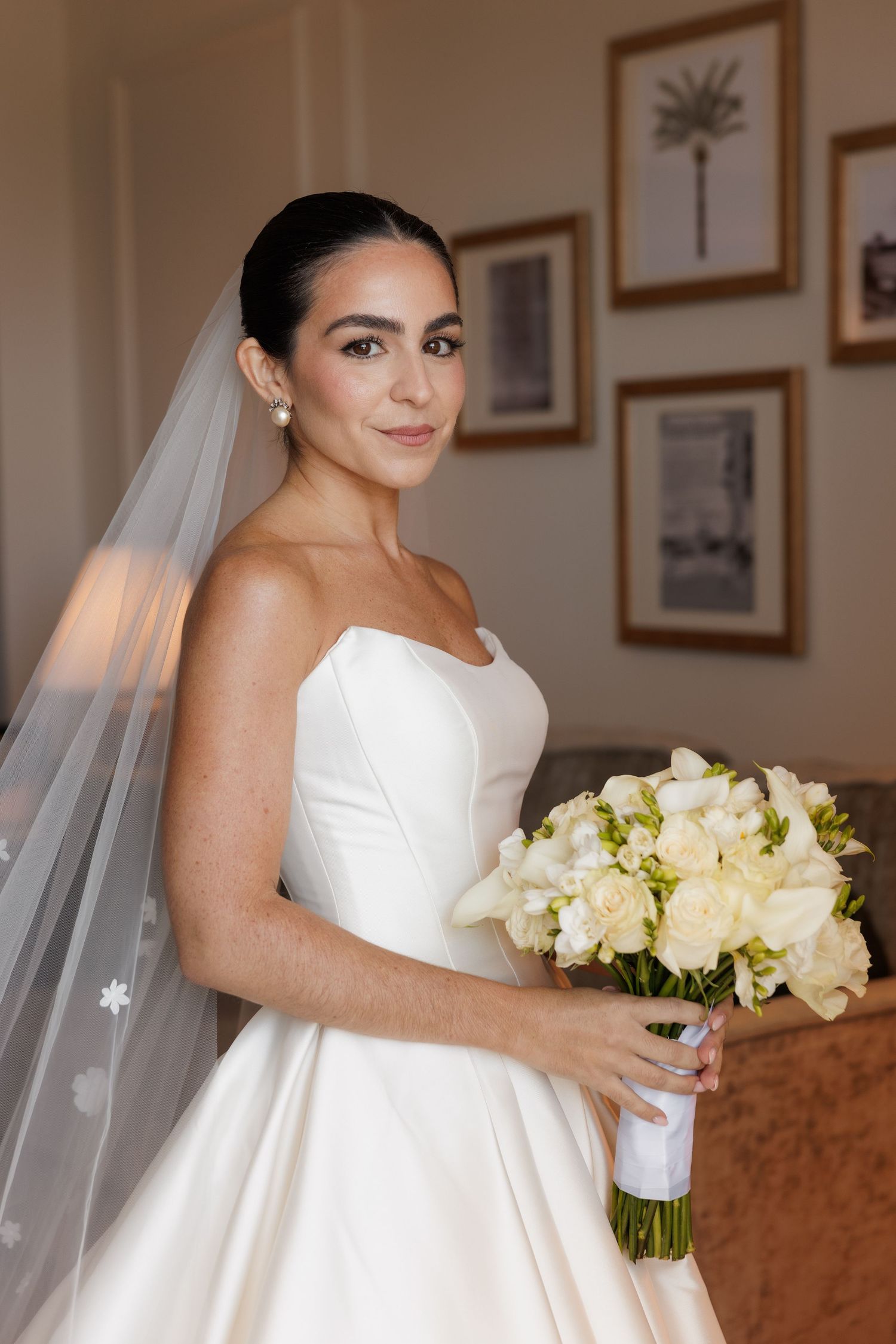An elegant bridal portrait featuring a classic white wedding gown and bouquet of cream roses.