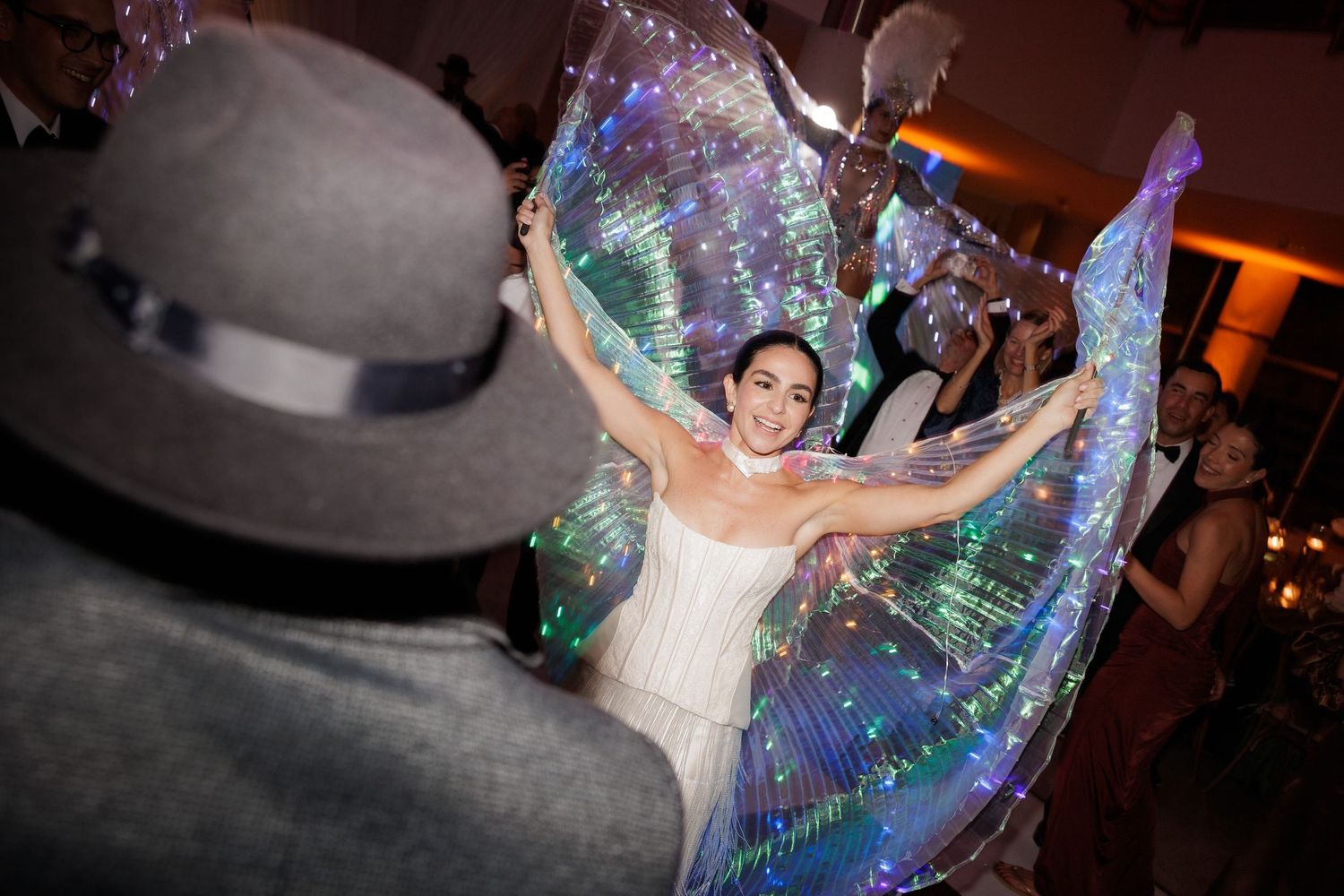 A person in a white dress dances joyfully under iridescent bubble decorations at an evening celebration.