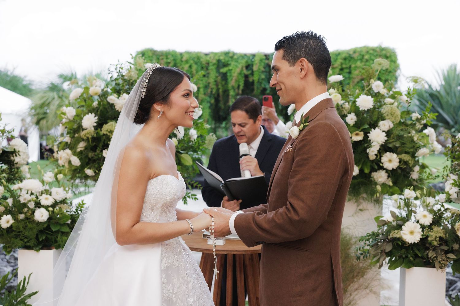 Outdoor wedding ceremony with white floral arrangements and natural garden backdrop.