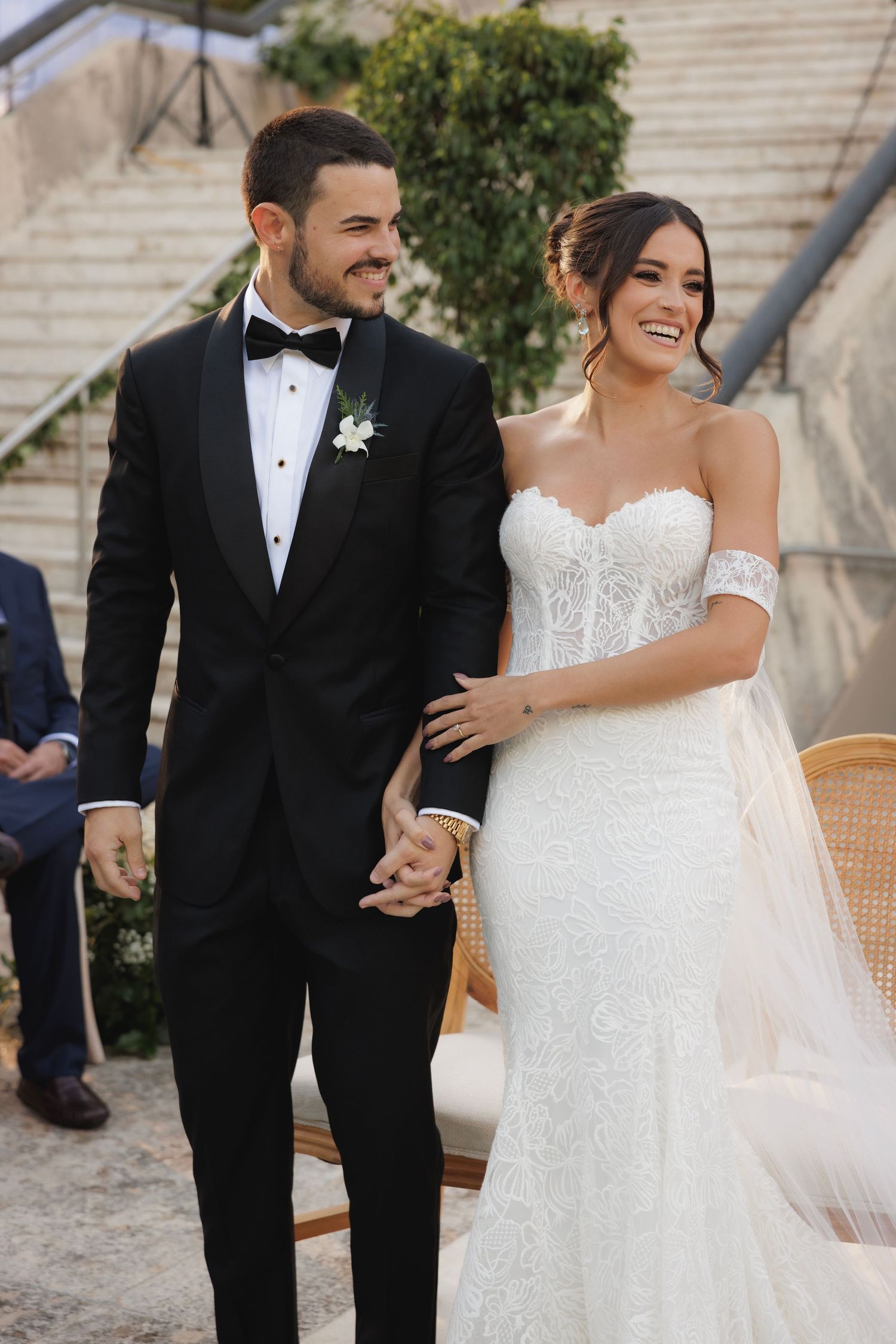A couple in wedding attire share joyful moments while walking together outdoors.