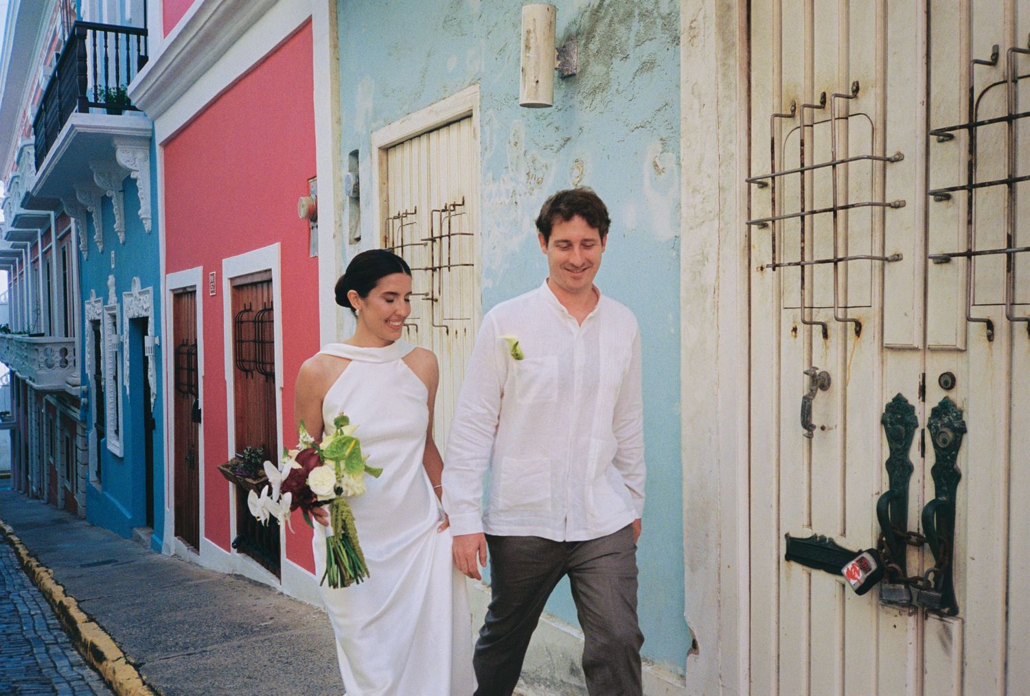 Bride and groom walk hand-in-hand on a colorful cobblestone street in Old San Juan, Puerto Rico.
