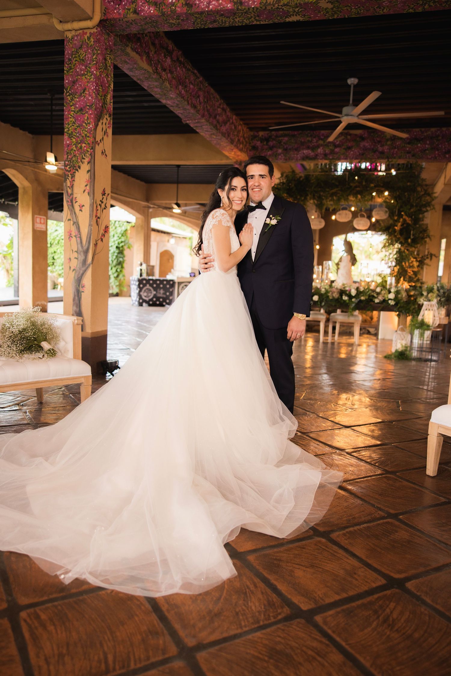 Elegant wedding couple twirling on a rustic tiled floor under romantic venue lighting.