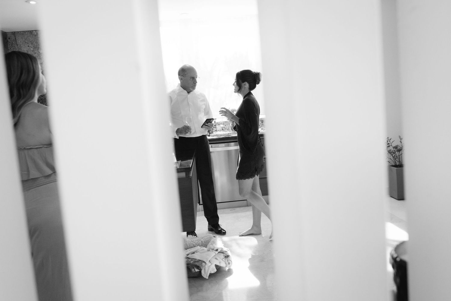 Black and white artistic wedding photography showing silhouettes against a white wall in a hallway setting.