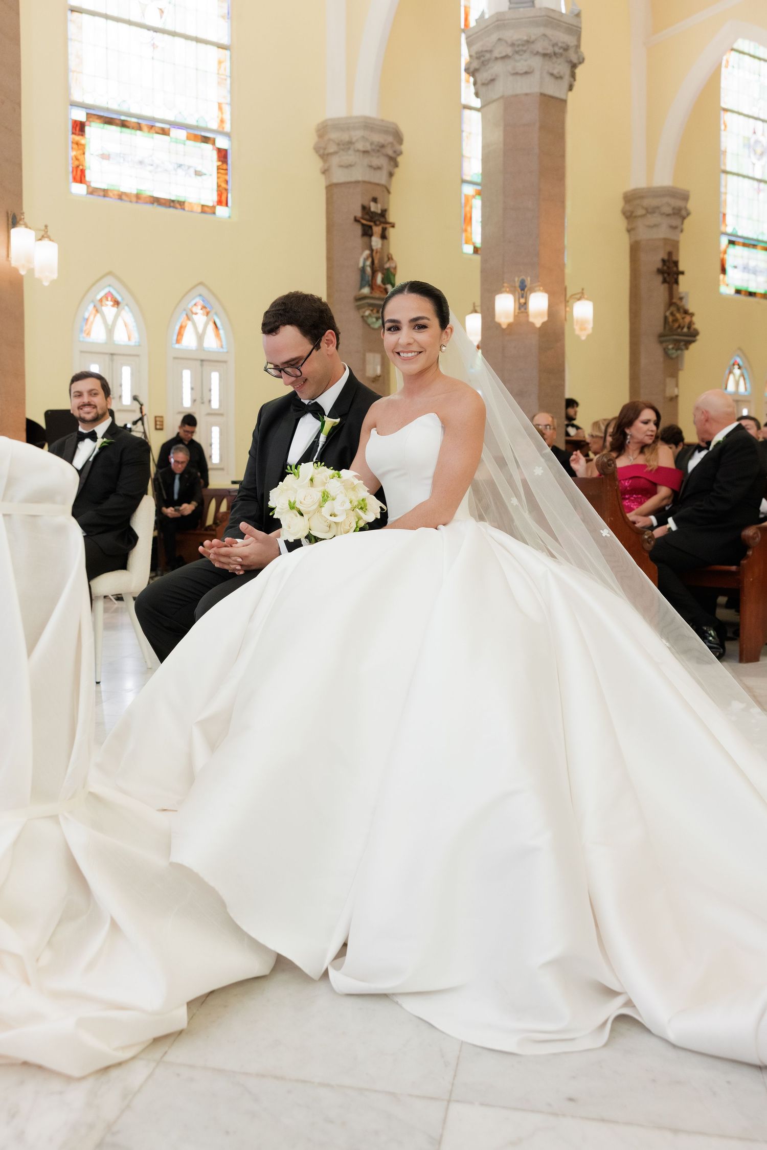 Dramatic full-length shot of white wedding gown against church pillars.