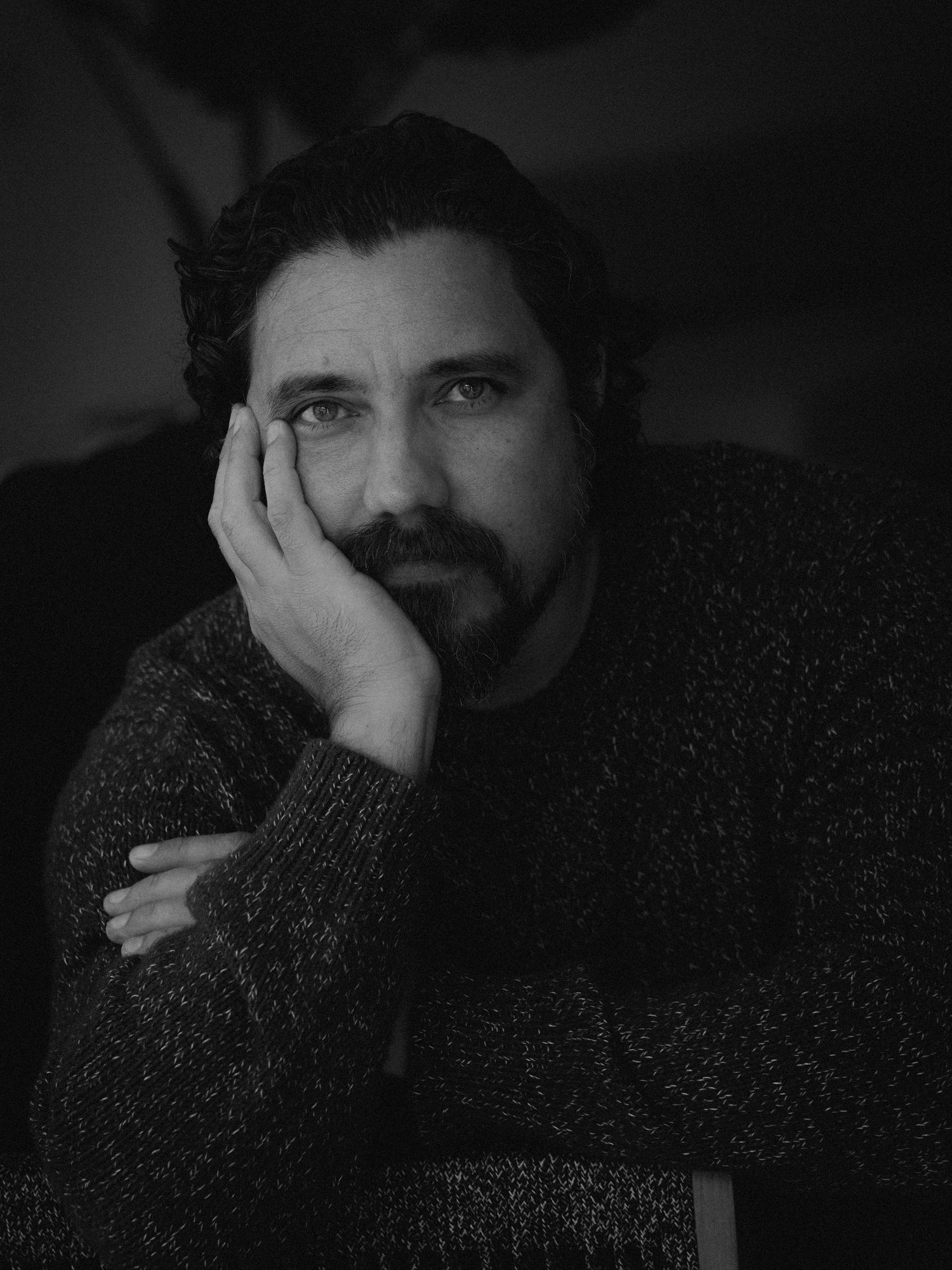 A series of black and white portraits showing someone covering their face with their hands in a dark sweater.
