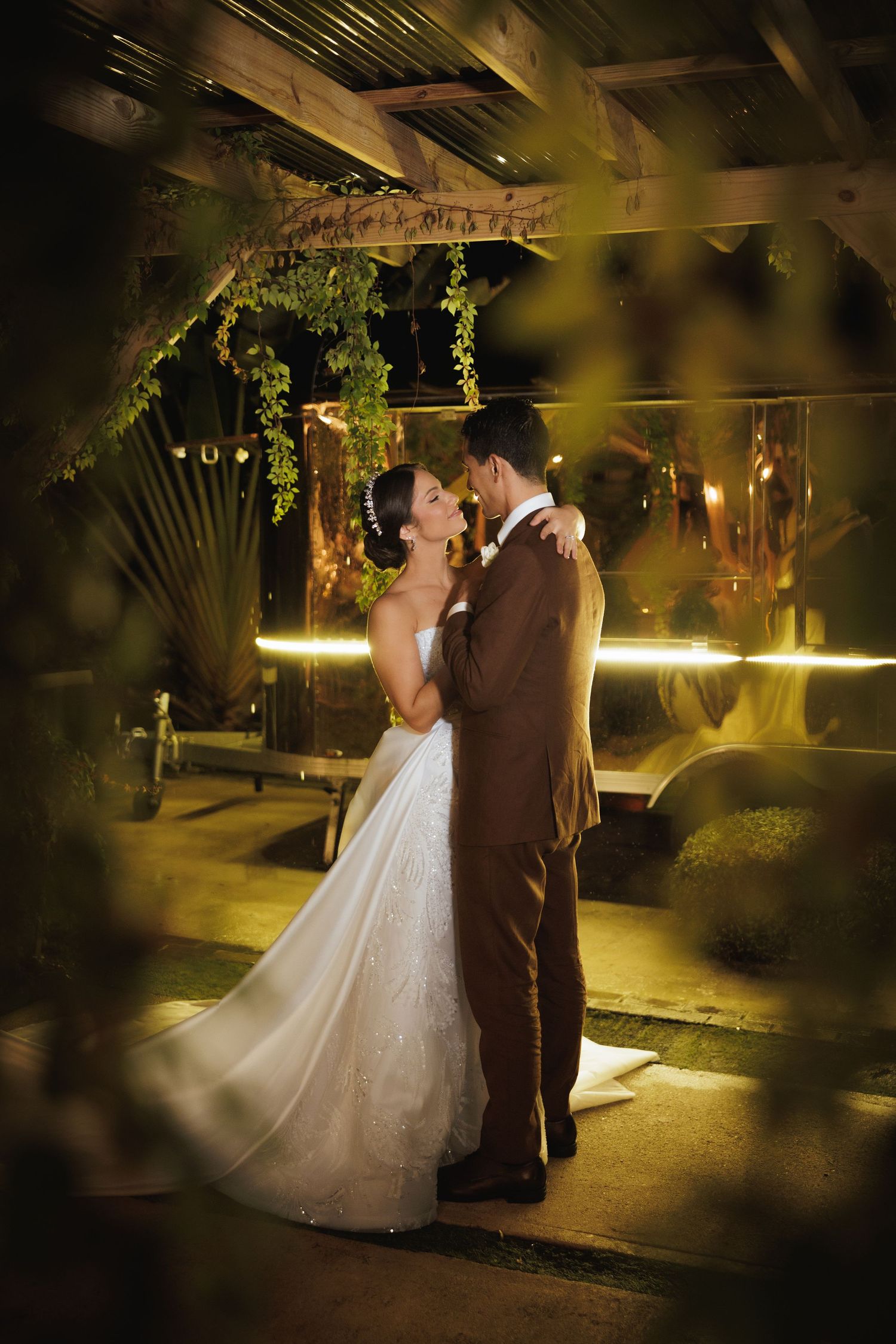 Newlyweds dance together in a romantic garden setting with warm ambient lighting.