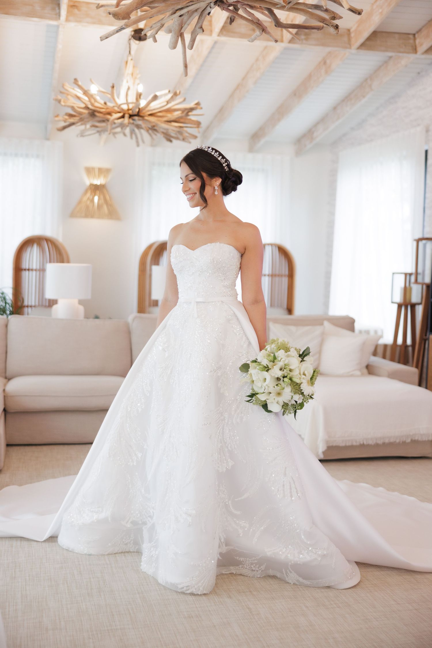 A bride in a stunning white ballgown twirls in an elegant room with wooden beam ceilings and modern decor.