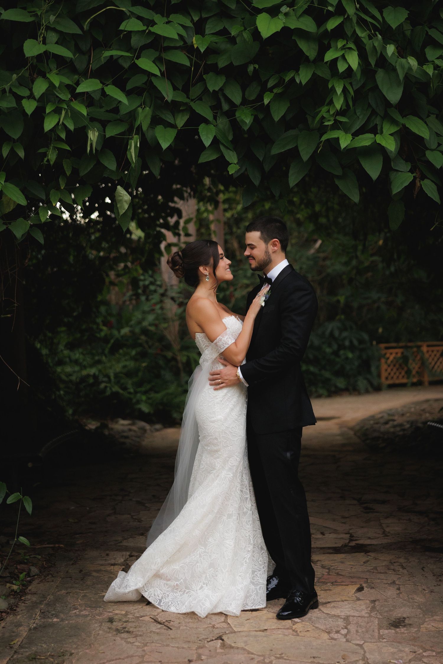 A couple shares an intimate moment in a lush garden setting during their wedding photoshoot.
