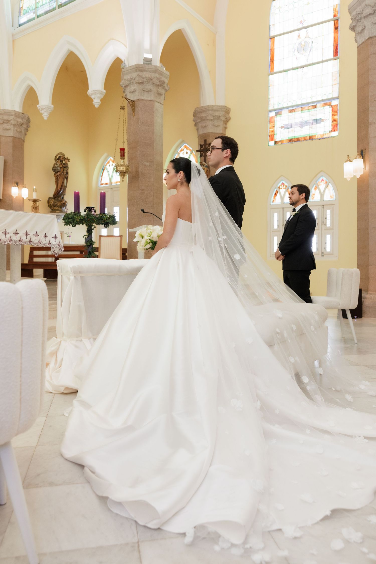 Wedding ceremony in ornate church with arched windows and columns.