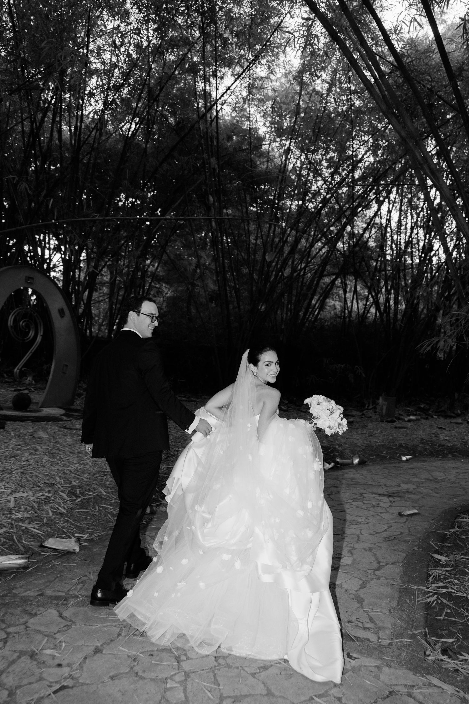 A series of black and white photos showing a couple walking along a stone path in a wooded area.