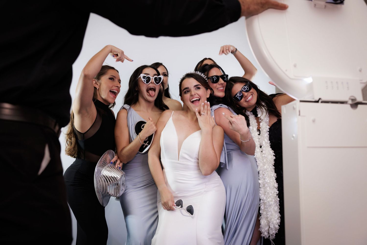 Wedding party members in coordinating gray and white dresses dance joyfully together at a celebration.
