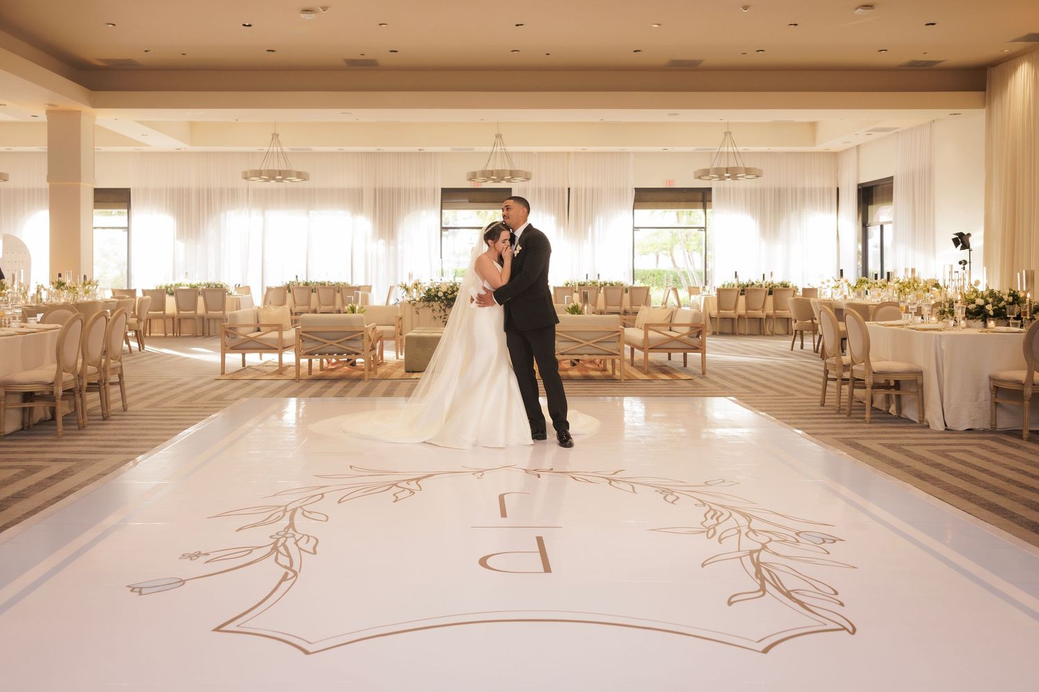 A panoramic view of an elegant white and beige wedding reception venue with tables set for a formal dinner celebration.