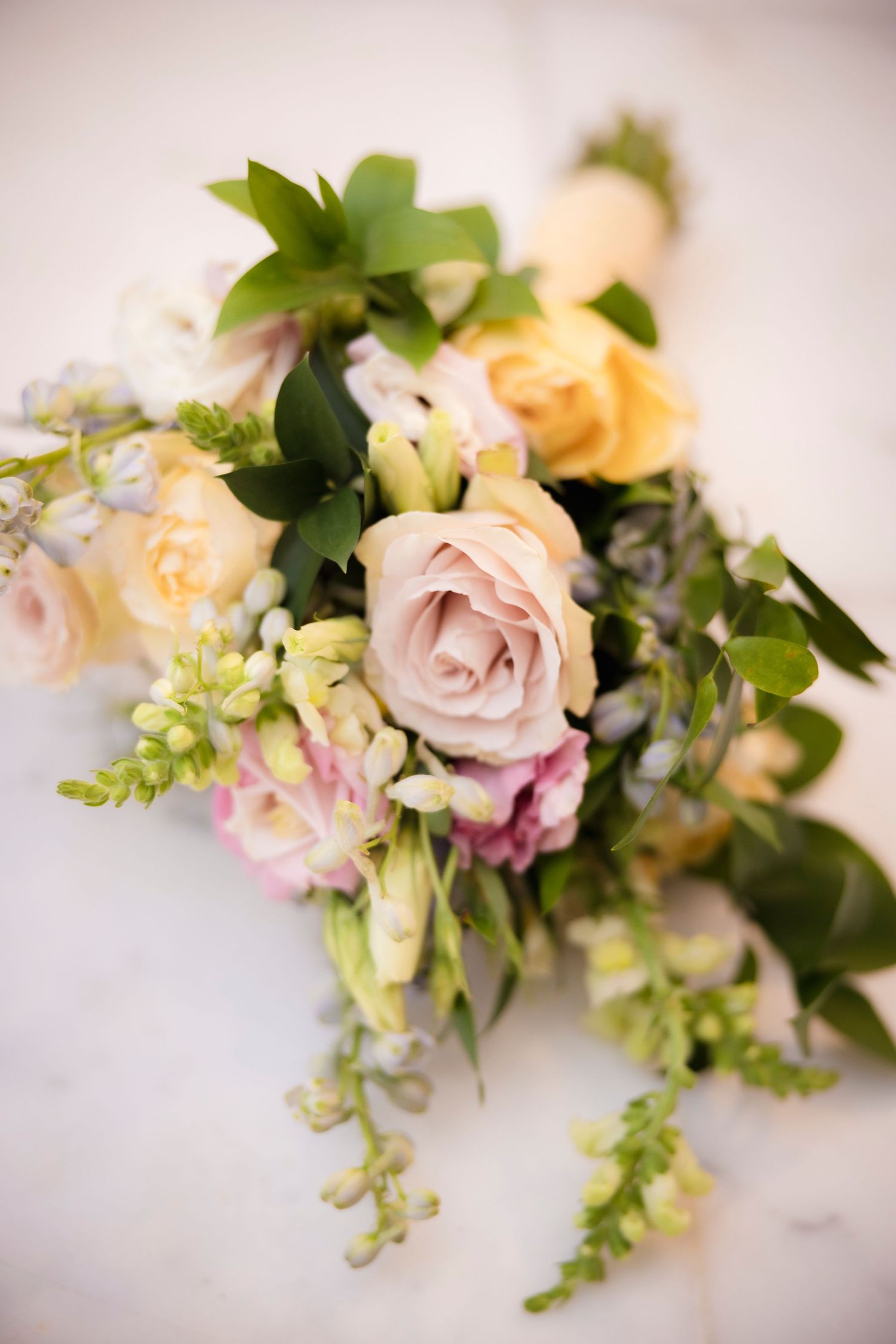 Delicate pink and cream roses with cascading greenery create a romantic wedding centerpiece.