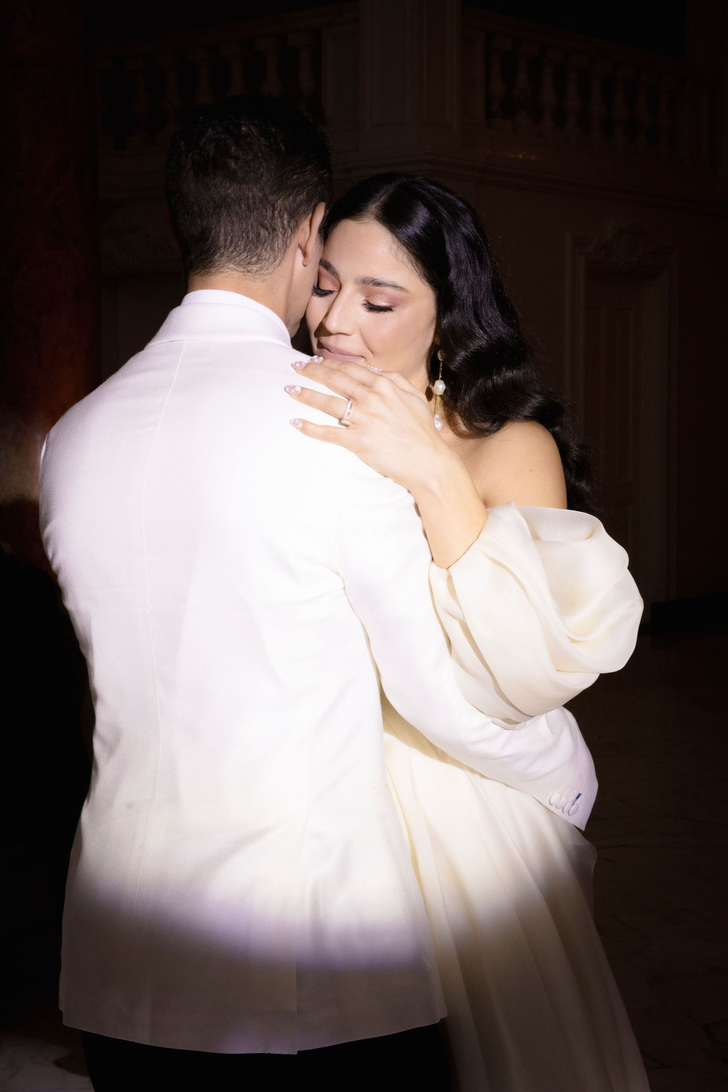 Intimate dance moment captured in dramatic lighting at wedding reception.