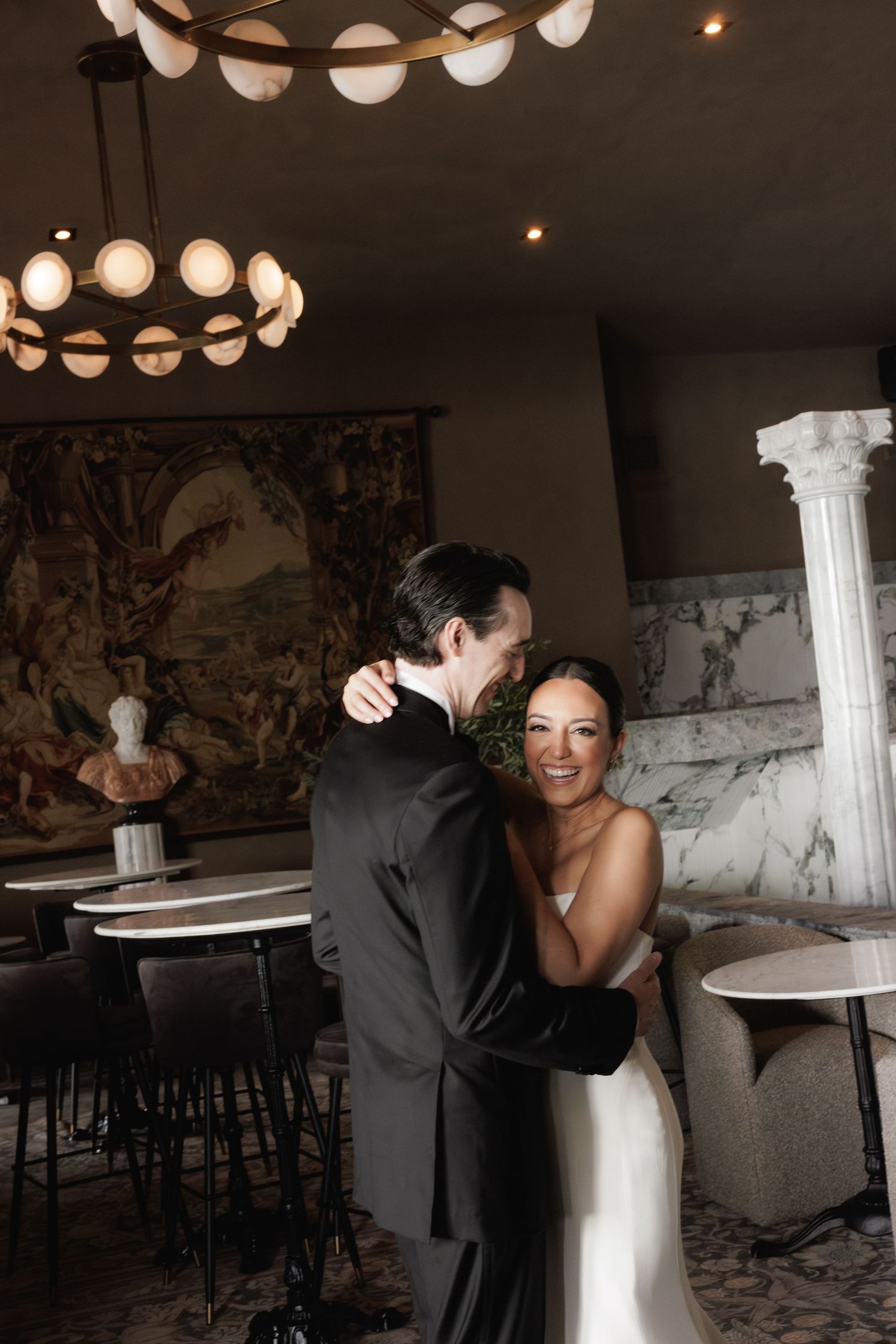 Romantic couple shares an intimate dance together in an elegant restaurant space with modern lighting fixtures.