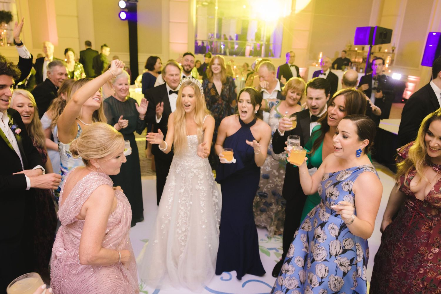Wedding reception dance party with guests celebrating in an elegantly lit ballroom.