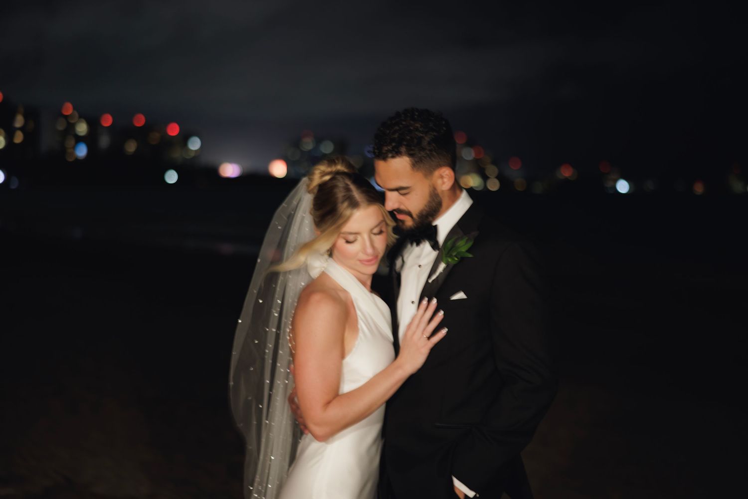 Romantic wedding couple dancing together in evening lighting with soft bokeh background.