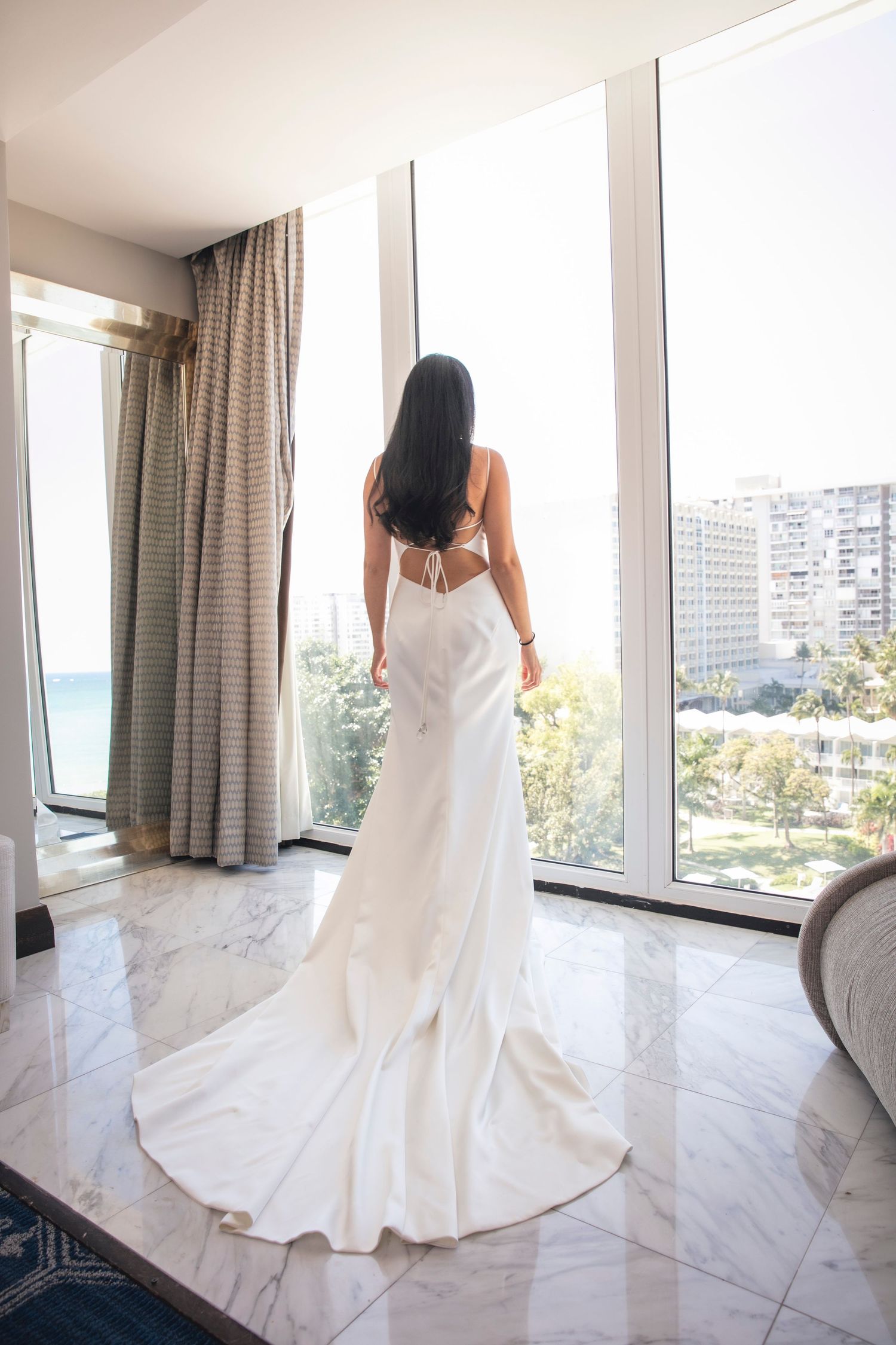 Elegant white wedding dress with long train photographed in modern room with ocean views.