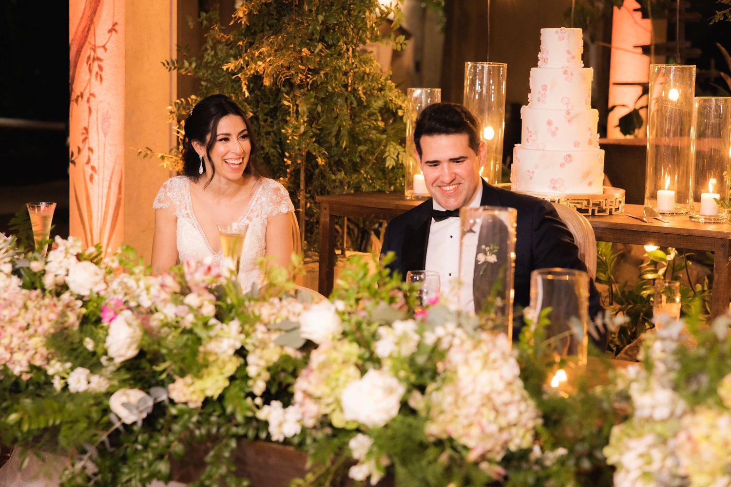 Five connected photos show a wedding reception table with glowing candles, white flowers and greenery in an elegant evening setting.
