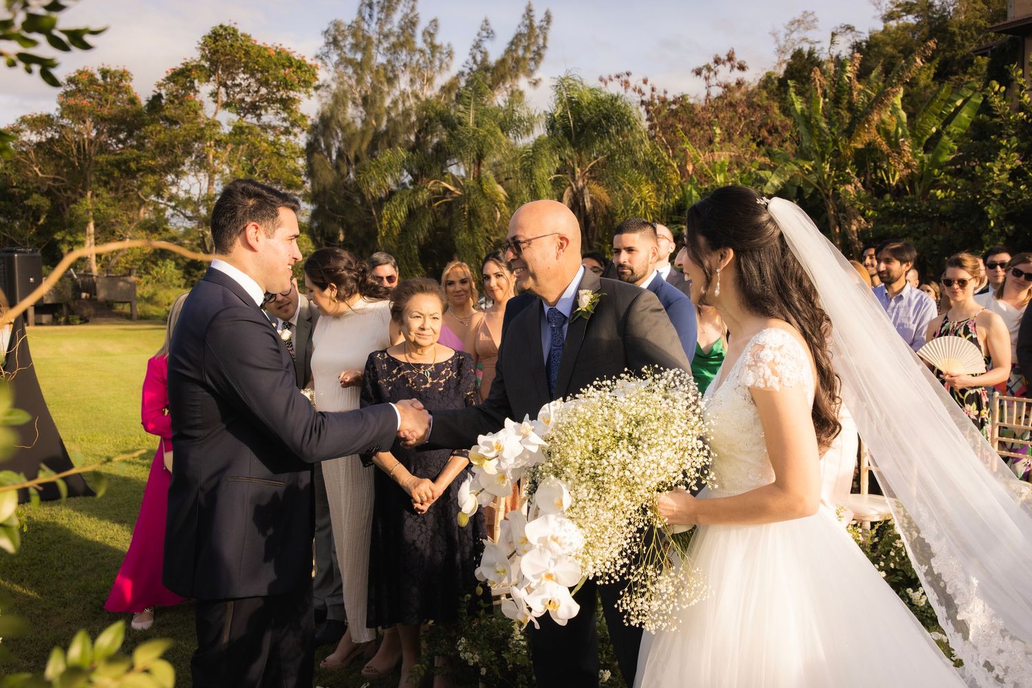 Wedding guests celebrate during an outdoor garden ceremony with white flower decorations.