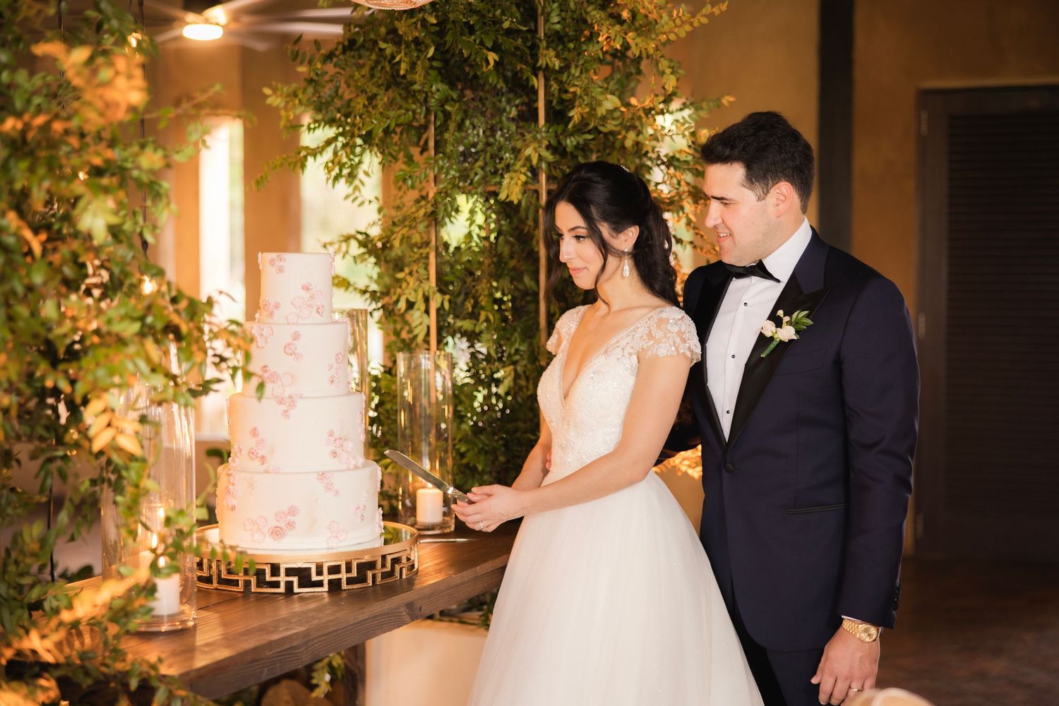 Wedding couple shares romantic moments under warm lighting with elegant greenery and floral decorations.