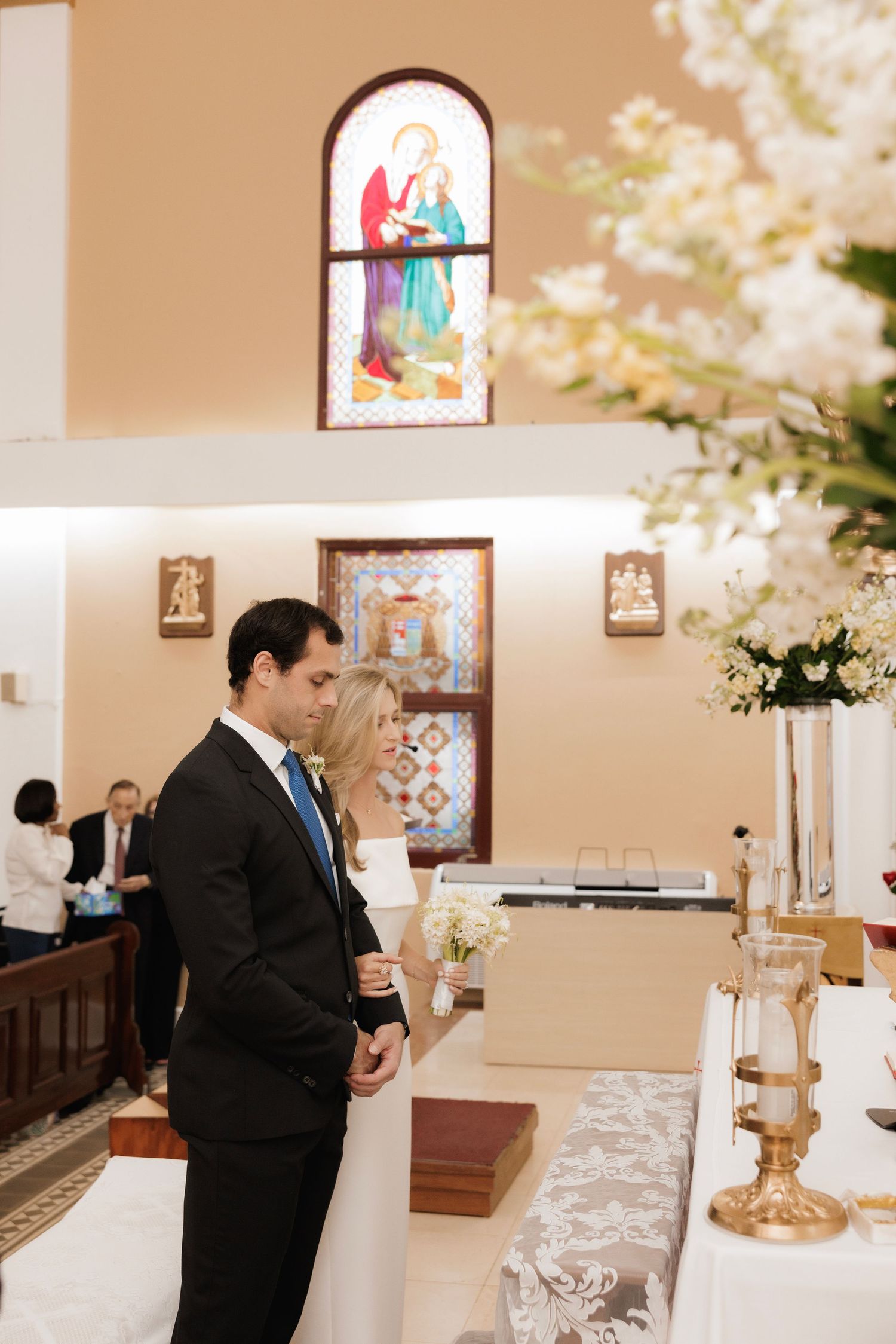 A church altar decorated with stained glass and candles during an intimate wedding ceremony.