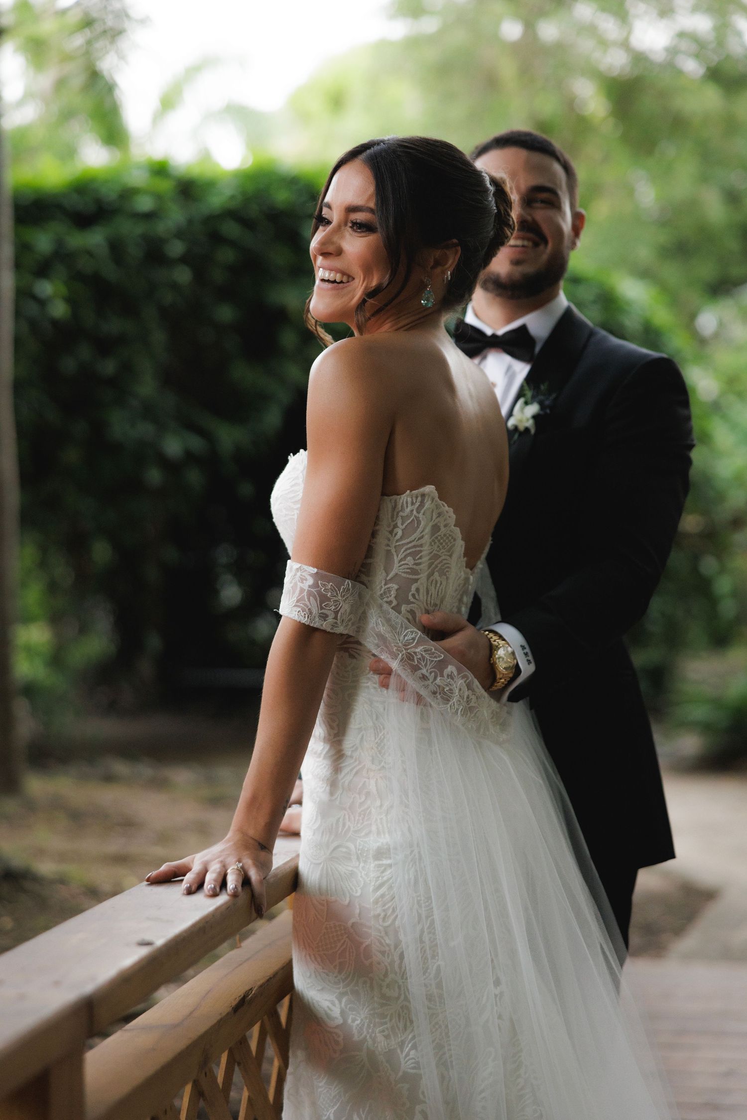 A couple shares an intimate moment on their wedding day in a lush garden setting with the bride in a stunning lace gown.