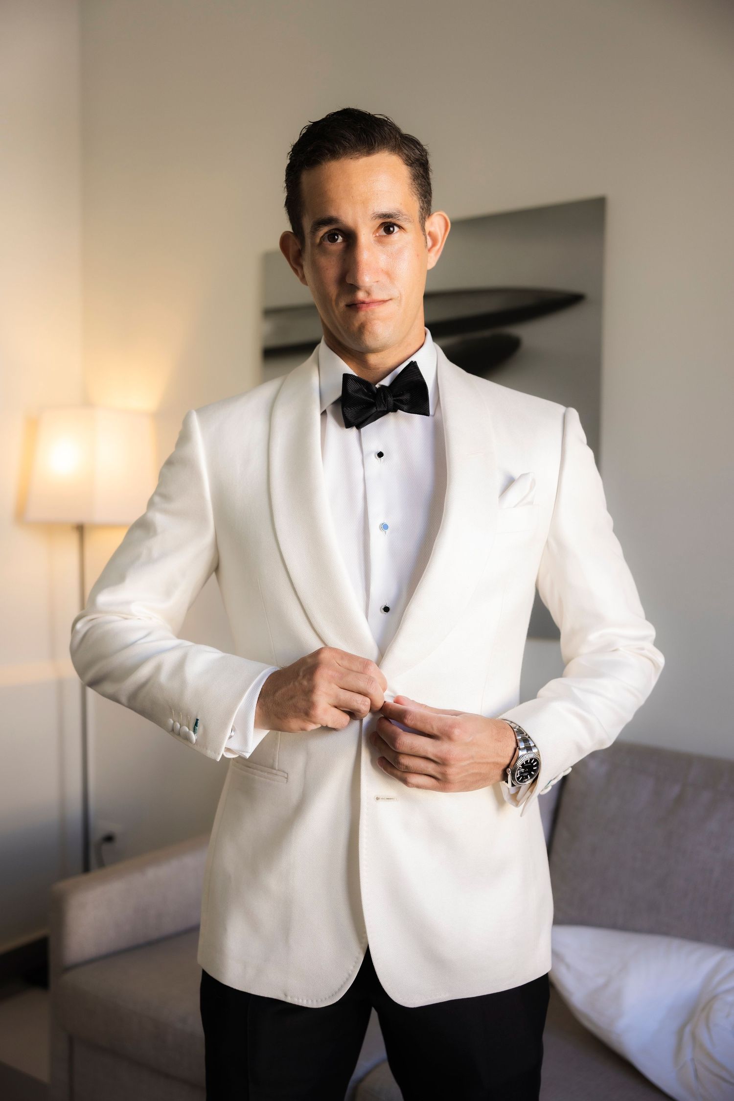 White tuxedo jacket being buttoned up during wedding day preparations.